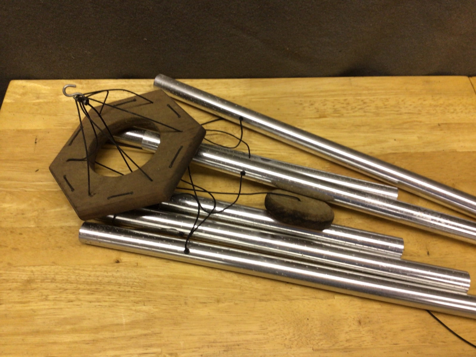 Hanging Wind Chime With Metal Tubes and Wooden Frame: The lot includes a hanging wind chime, comprised of cylindrical metal tubes, a hexagonal wooden top frame, a wooden clapper for sound production, and a triangular wooden windcatcher