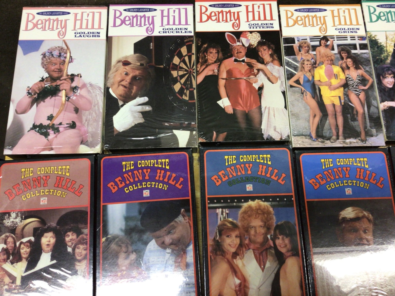 Benny Hill, The Honeymooners, and Red Skelton VHS Box Sets: This lot includes multiple VHS box sets featuring Benny Hill, The Honeymooners, Red Skelton, The Three Stooges, and more. The Benny Hill sets include titles such as 'Golden Smiles,' 'Golden Yucks,'