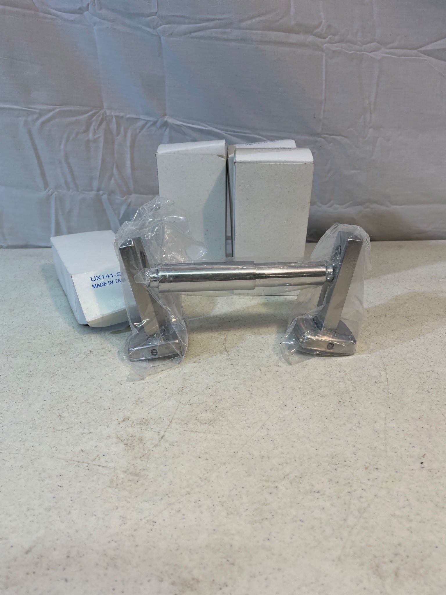 Toilet Paper Dispenser Lot with Wall-Mounting Fixtures: This lot includes a set of chrome-finish toilet paper dispensers, complete with wall-mounting hardware. Items are packaged and include screws for installation. The dispensers are labeled as model