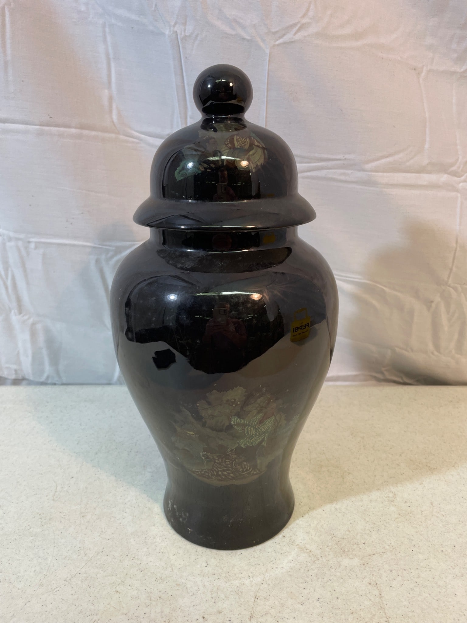 Black Lidded Ceramic Ginger Jar with Floral and Animal Motif: This listing is for a black ceramic ginger jar with a matching lid. The jar is decorated with subtle floral and animal motifs. The interior is cream-colored. Specific manufacturer and model details ar