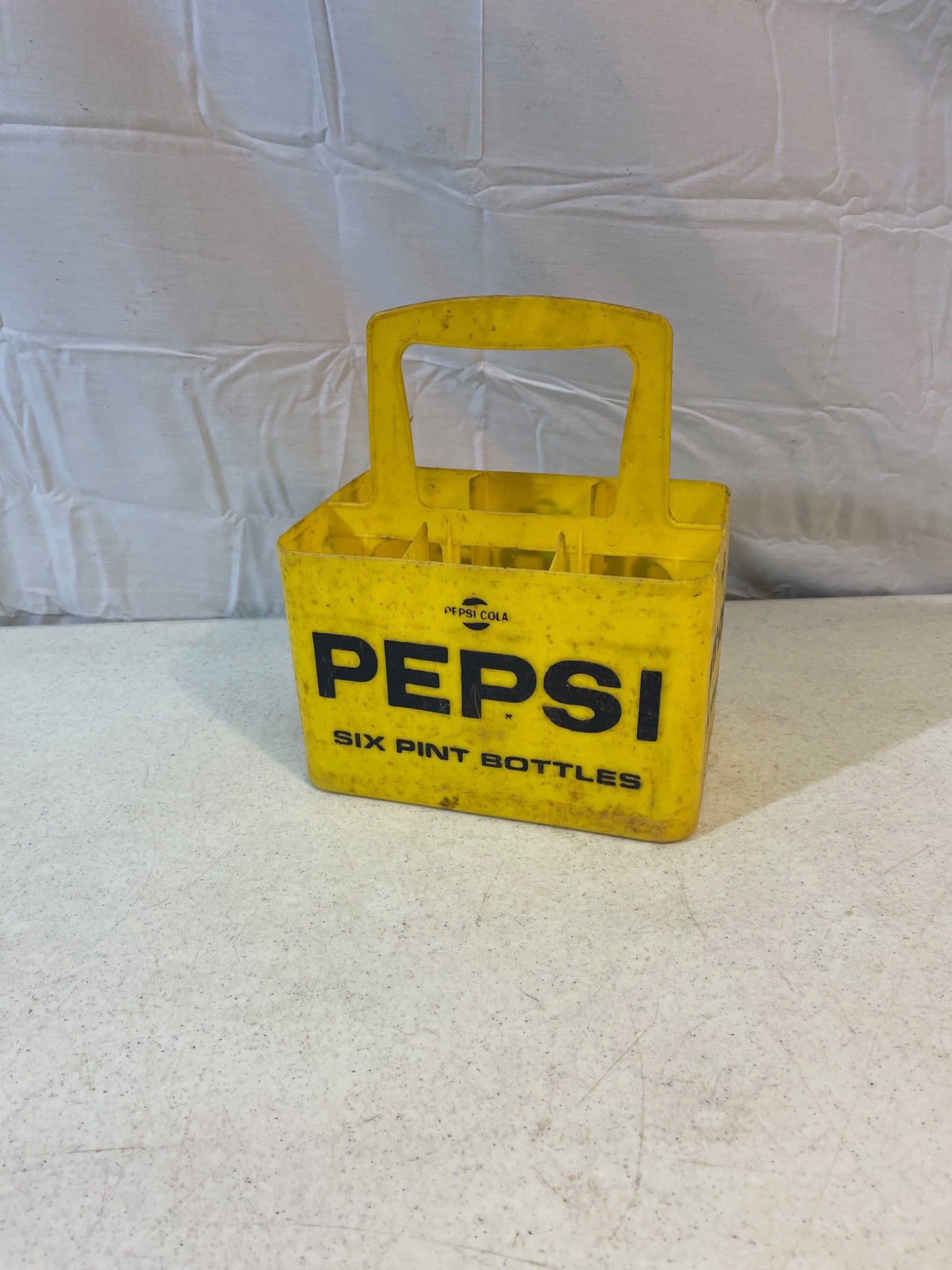 Pepsi-Cola Yellow Six-Bottle Plastic Crate Carrier for Pint and 16-Ounce Bottles: Pepsi-Cola branded plastic bottle carrier designed for six pint bottles or six 16-ounce bottles. Likely manufactured mid-to-late 20th century based on design. Yellow plastic construction with black