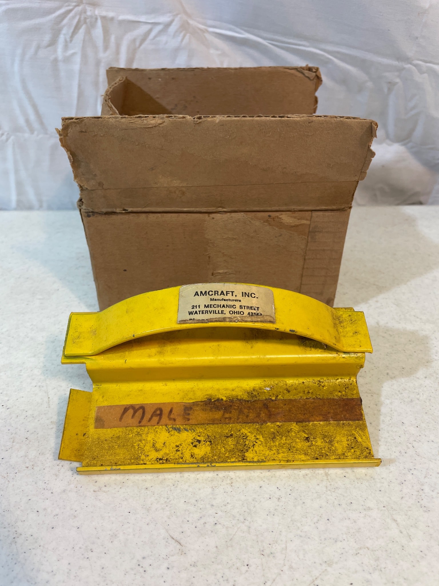 Amcraft, Inc. Male Die Cutting Tool with Original Box: This is a male die cutting tool manufactured by Amcraft, Inc., located at 917 Mechanic Street, Waterville, Ohio. The tool features a yellow-painted metal body with a cutting blade and includes its