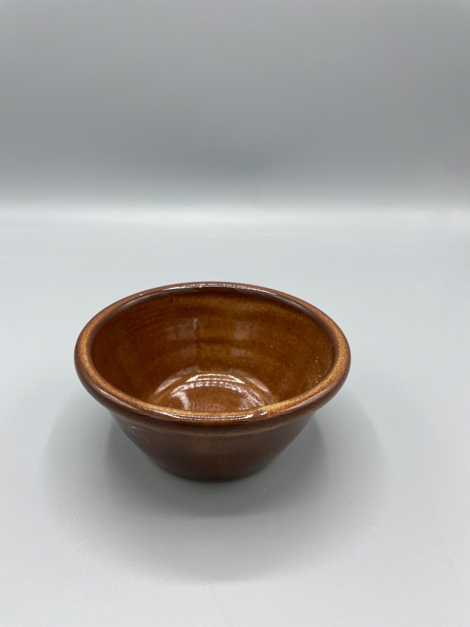 Small Ceramic Bowl, LMS 2002, Marked on Base: This is a small ceramic bowl with a brown glaze. The base is stamped with the text 'LMS' and the year '2002,' along with what appears to be a manufacturerâ€™s mark. The piece is