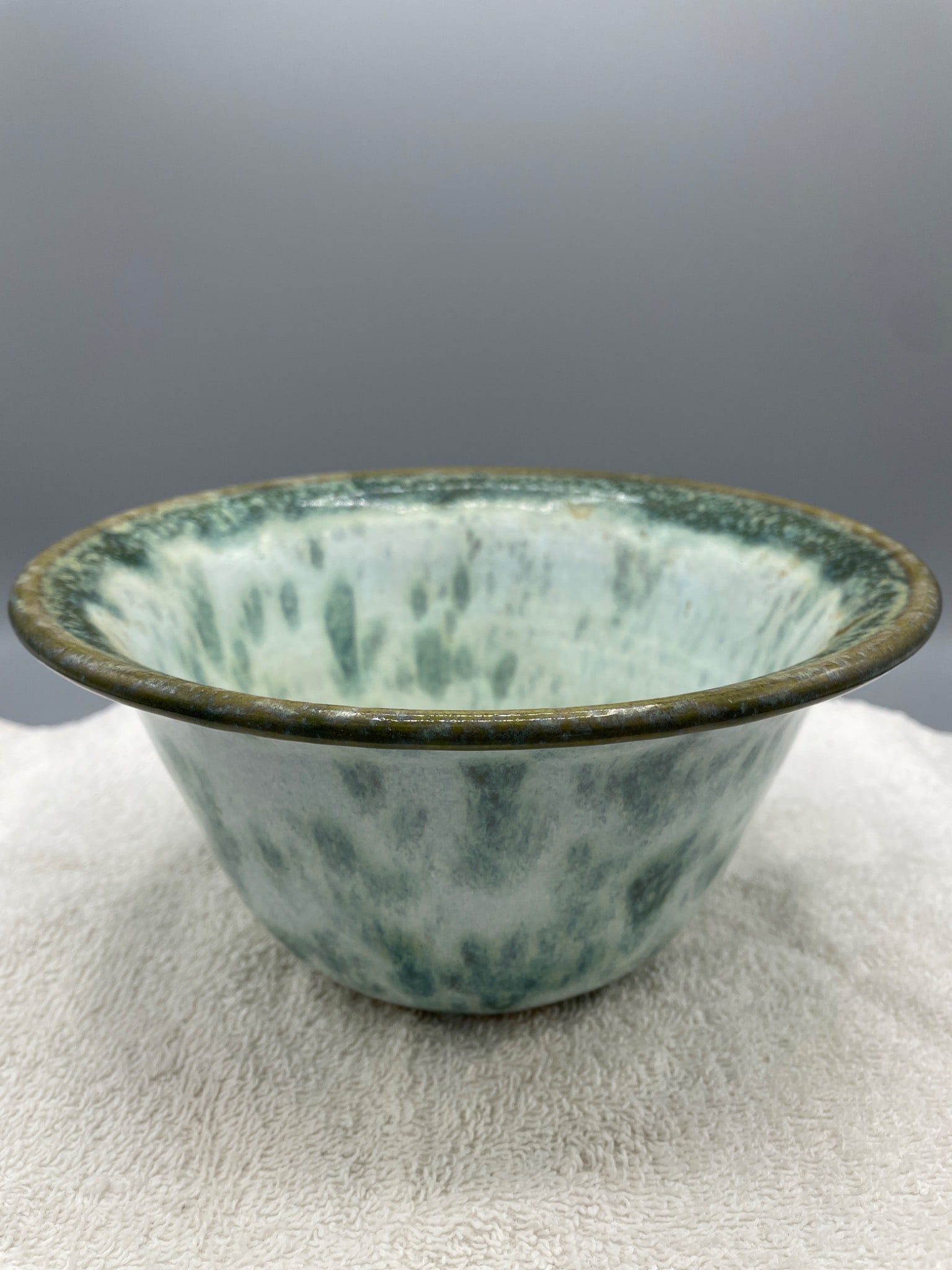 Handmade Glazed Ceramic Bowl with Signature, Approximately 4 Inches Tall: This is a handmade ceramic bowl with a green and white glazed finish. The piece measures approximately 4 inches in height and features an engraved signature on the base, which reads 'Potluck' and an