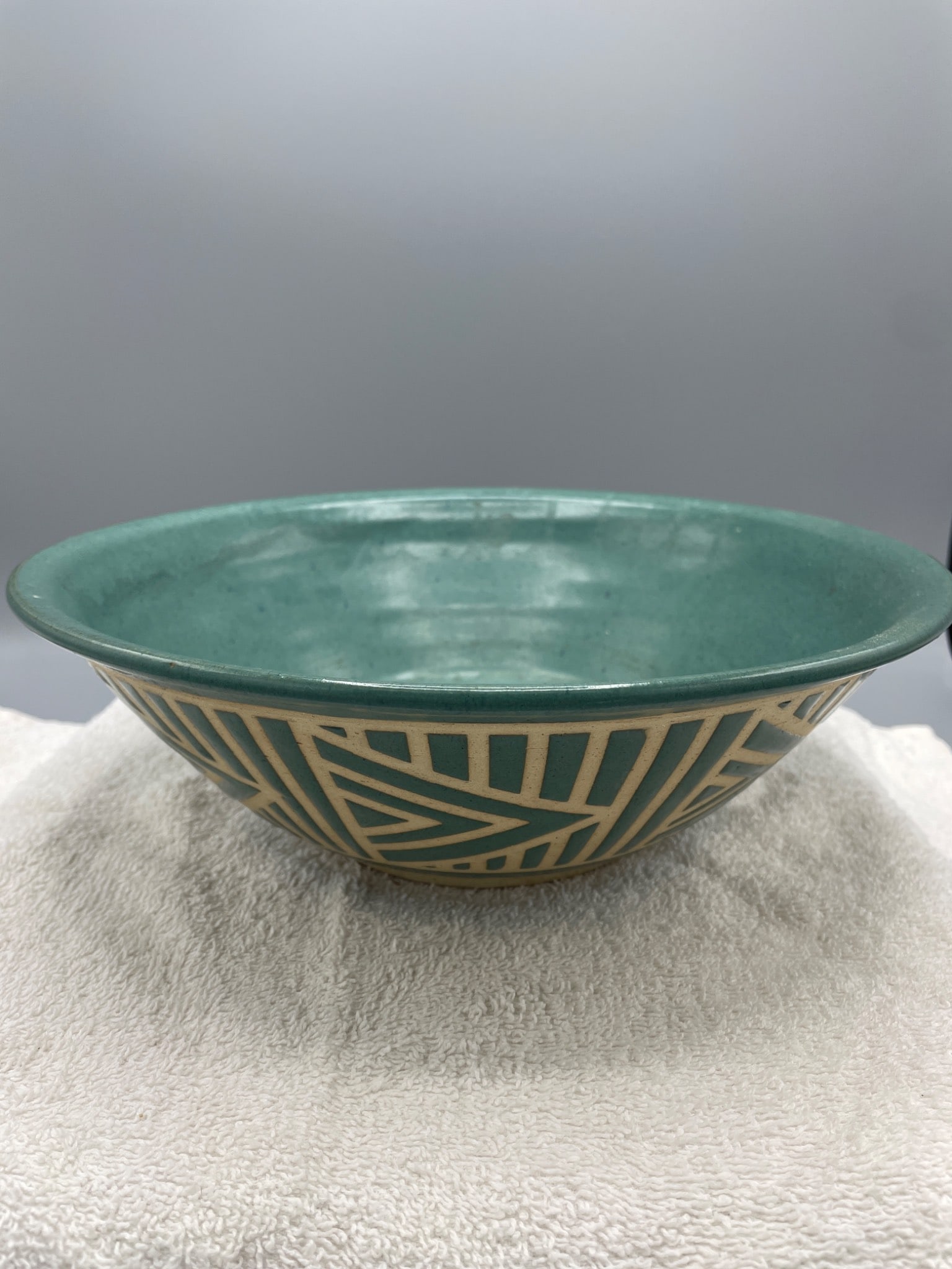 Ceramic Bowl With Geometric Pattern Signed 'Hughes': A ceramic bowl with a turquoise glaze interior and a beige and turquoise geometric patterned exterior. Signed on the base with 'Hughes.' Measures approximately 2.5 inches in height, as shown in the