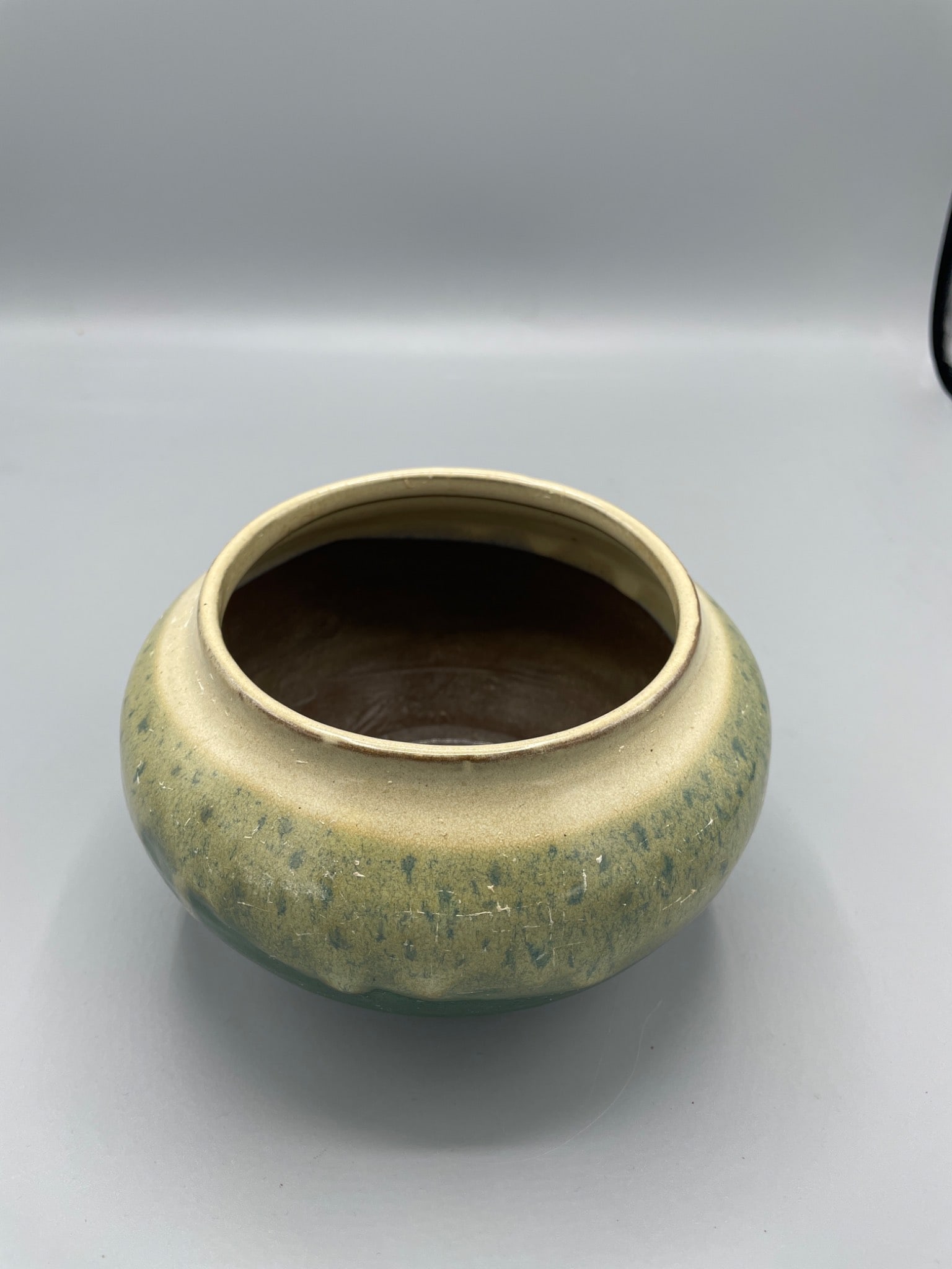 Glazed Ceramic Bowl with Multicolor Exterior, Approx. 5 Inches Tall: This is a ceramic bowl featuring a glazed multicolor exterior with a green and beige finish. The interior has a glossy brown glaze, and the bottom is unglazed featuring a red clay base. The bowl