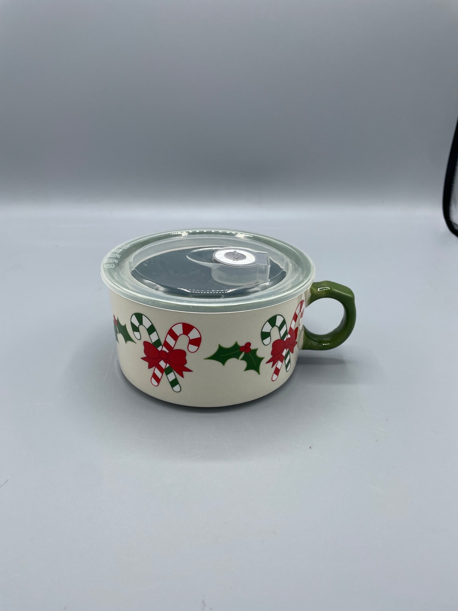 Temp-tations Winter Whimsy 22 oz Mug With Lid, Oven/Dishwasher/Microwave Safe: Temp-tations Winter Whimsy mug featuring a 22 oz capacity, decorated with a candy cane and holly motif. Includes a clear plastic lid for sealing. Marked as oven, dishwasher, and microwave safe. Model