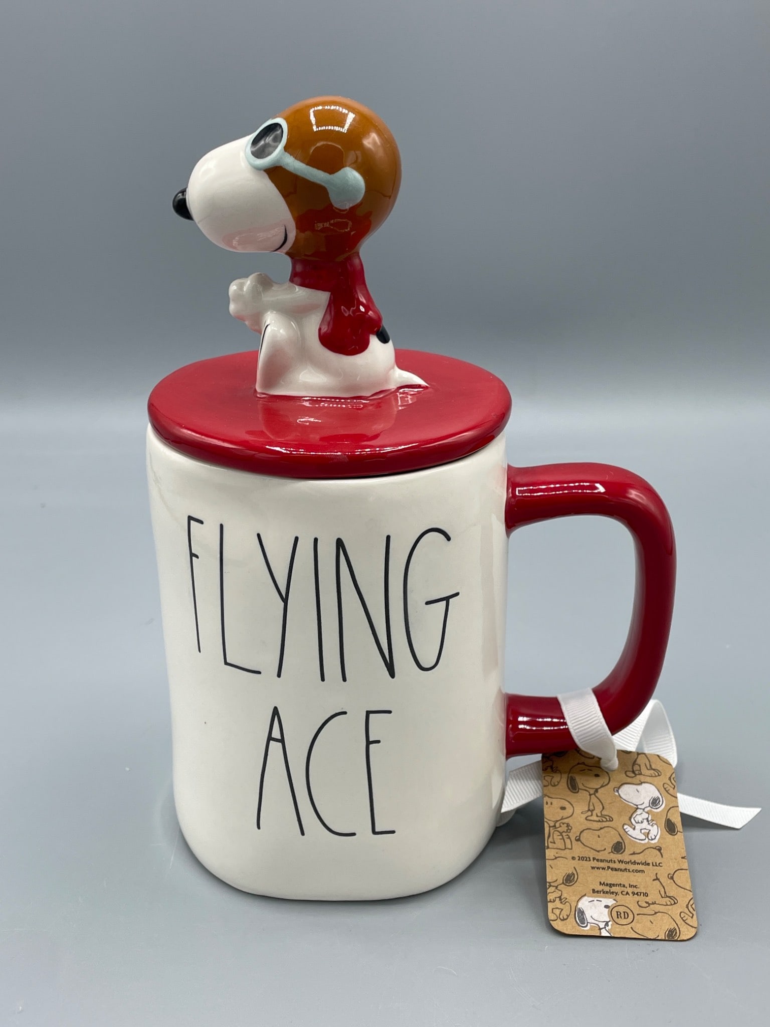 Rae Dunn Peanuts Flying Ace Mug With Lid, 2023, Ceramic: This is a ceramic mug from the Rae Dunn Artisan Collection by Magenta, featuring the Peanuts character Snoopy as the Flying Ace. It includes a matching lid with a Snoopy figurine in pilot gear. The