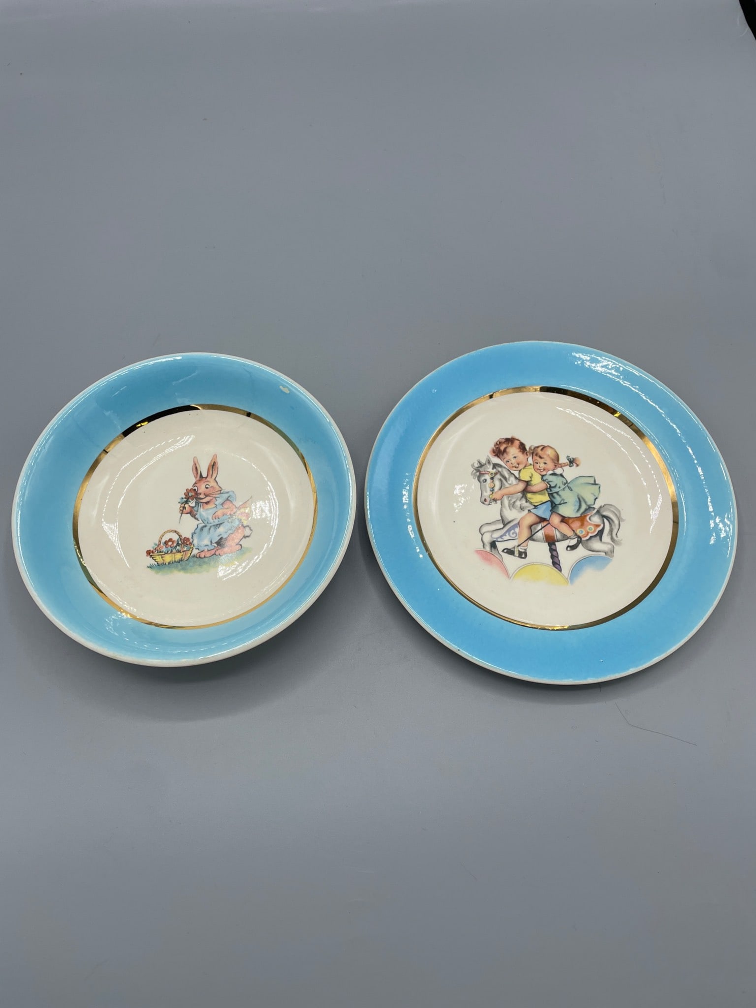 Salem China Co. Porcelain Bowls with Blue Trim and 23-Karat Gold Accent: Two porcelain bowls produced by Salem China Co., Salem, Ohio, USA. Decorated with light blue trim and 23-karat gold accents. Each features different designs on the plates: one with a bunny and Easter