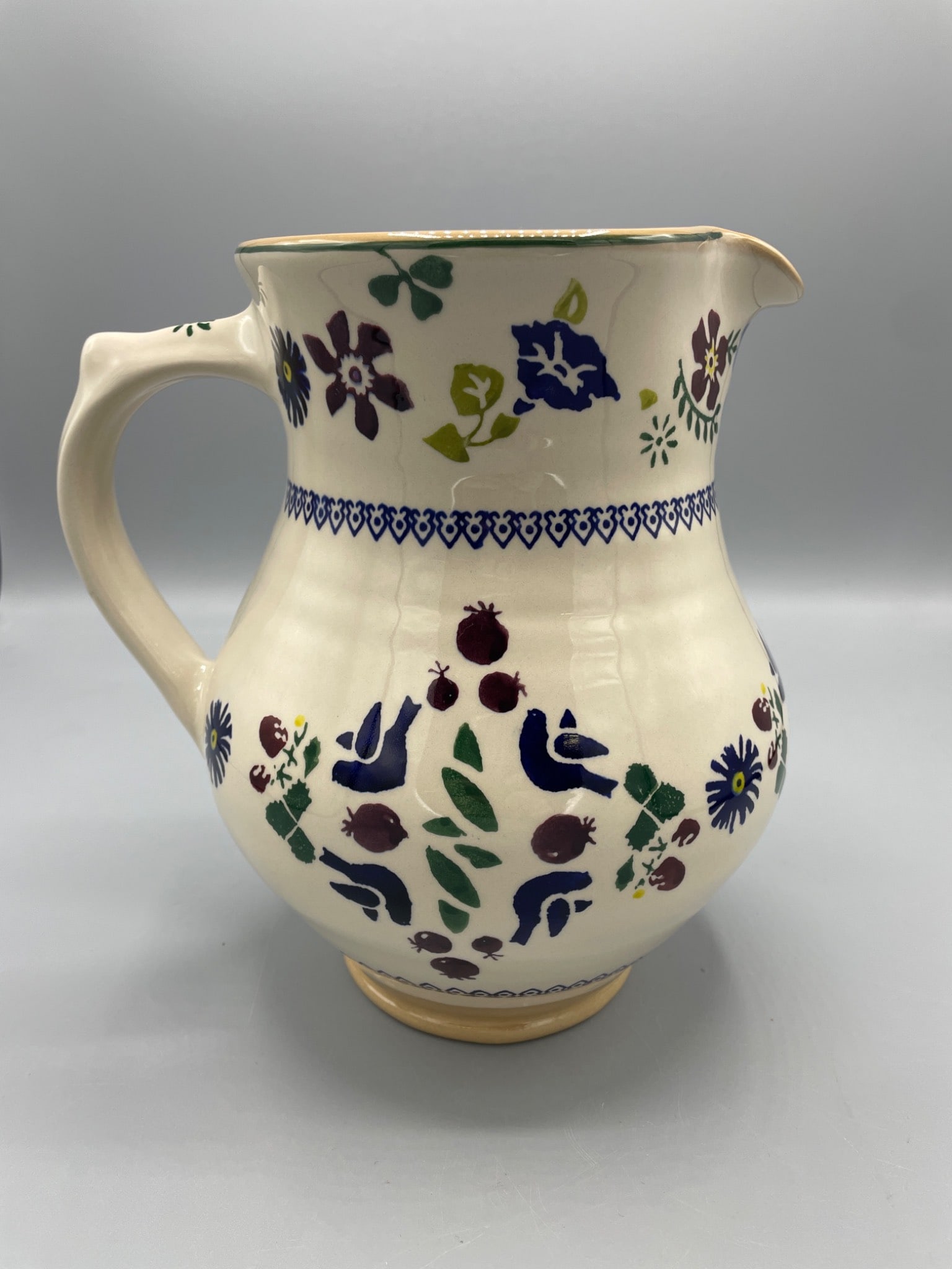 Nicholas Mosse Pottery Irish Handcrafted Jug with Floral Design: This handcrafted jug by Nicholas Mosse Pottery measures approximately 7.5 inches tall and features a floral and bird motif with hand-painted detailing. The piece is stamped on the base with 'Nicholas 