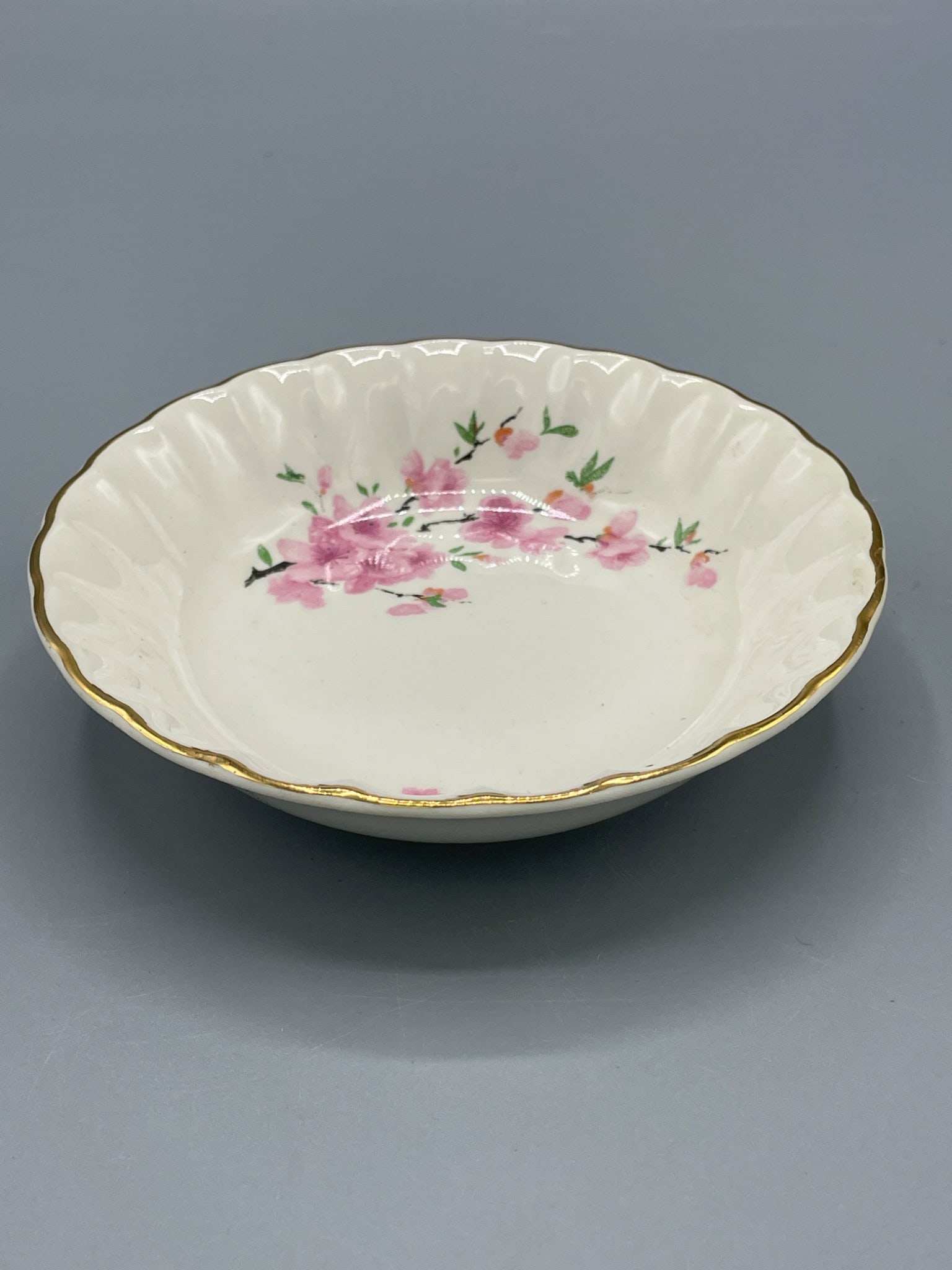 W.S. George Bolero 136D Pink Floral Pattern Bowl with Gold Trim: This bowl is marked W.S. George Bolero 136D on the base. It features a pink floral pattern, gold trim, and a scalloped edge. The bowl measures approximately 1.5 inches in height as shown in the