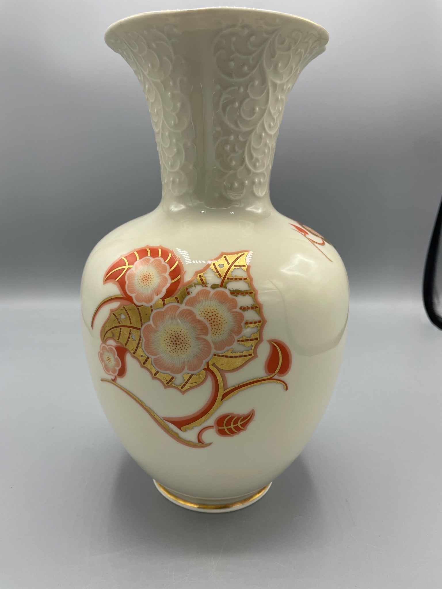 Sorau Porcelain Vase With Floral Motif and Embossed Design, 8.5 Inches: A Sorau porcelain vase featuring ornate floral motifs and embossed detailing near the neck. The underside bears the Sorau hallmark, with a crown and wreath emblem, marked with the number '89.' The