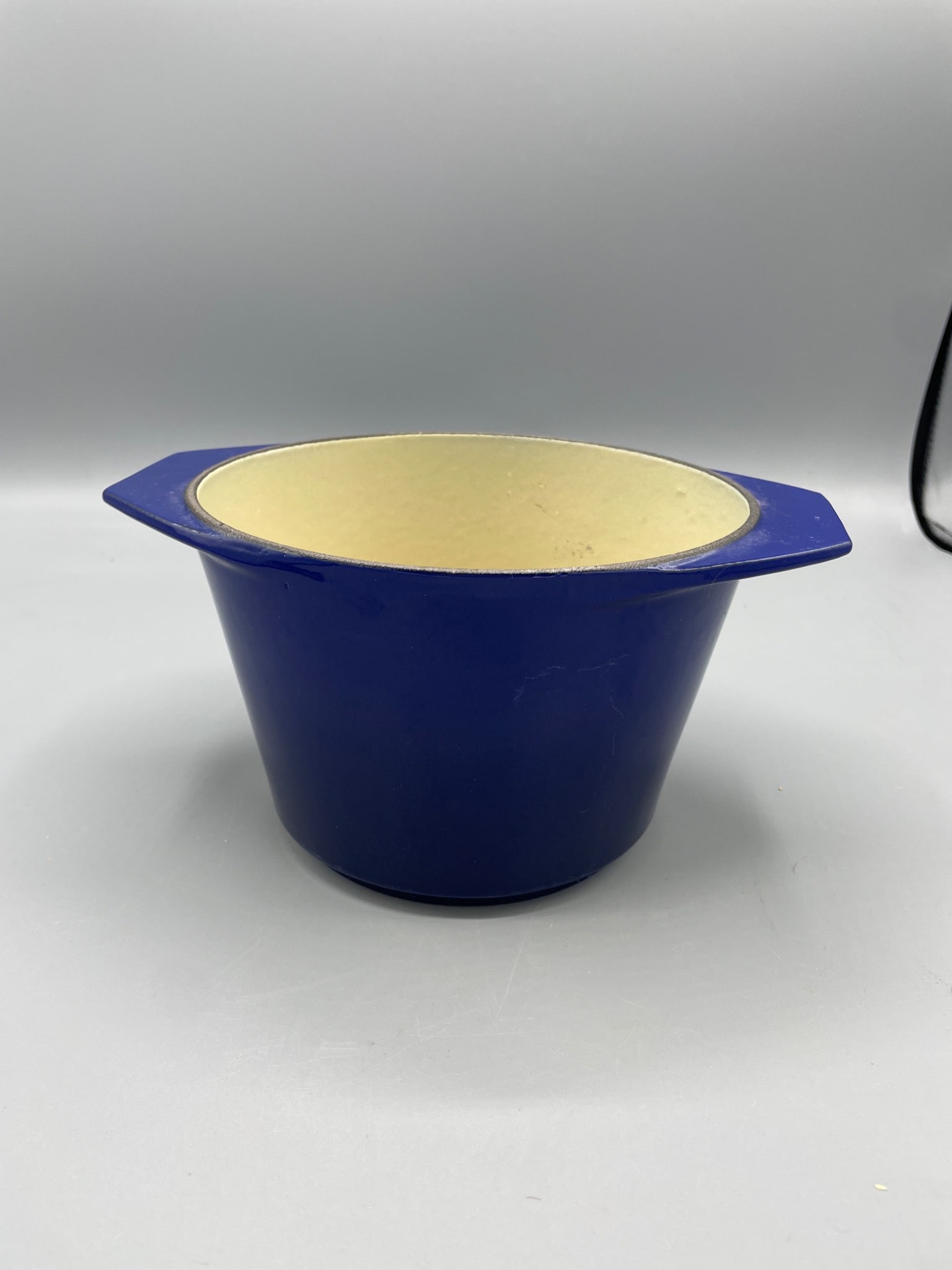 Blue Enameled Cast Iron Cooking Pot with Dual Handles, 6 In. Tall: Enamel-coated cast iron cooking pot featuring a vibrant blue exterior and ivory interior. The pot is 6 inches in height and has dual handles for easy handling. The bottom is embossed with an