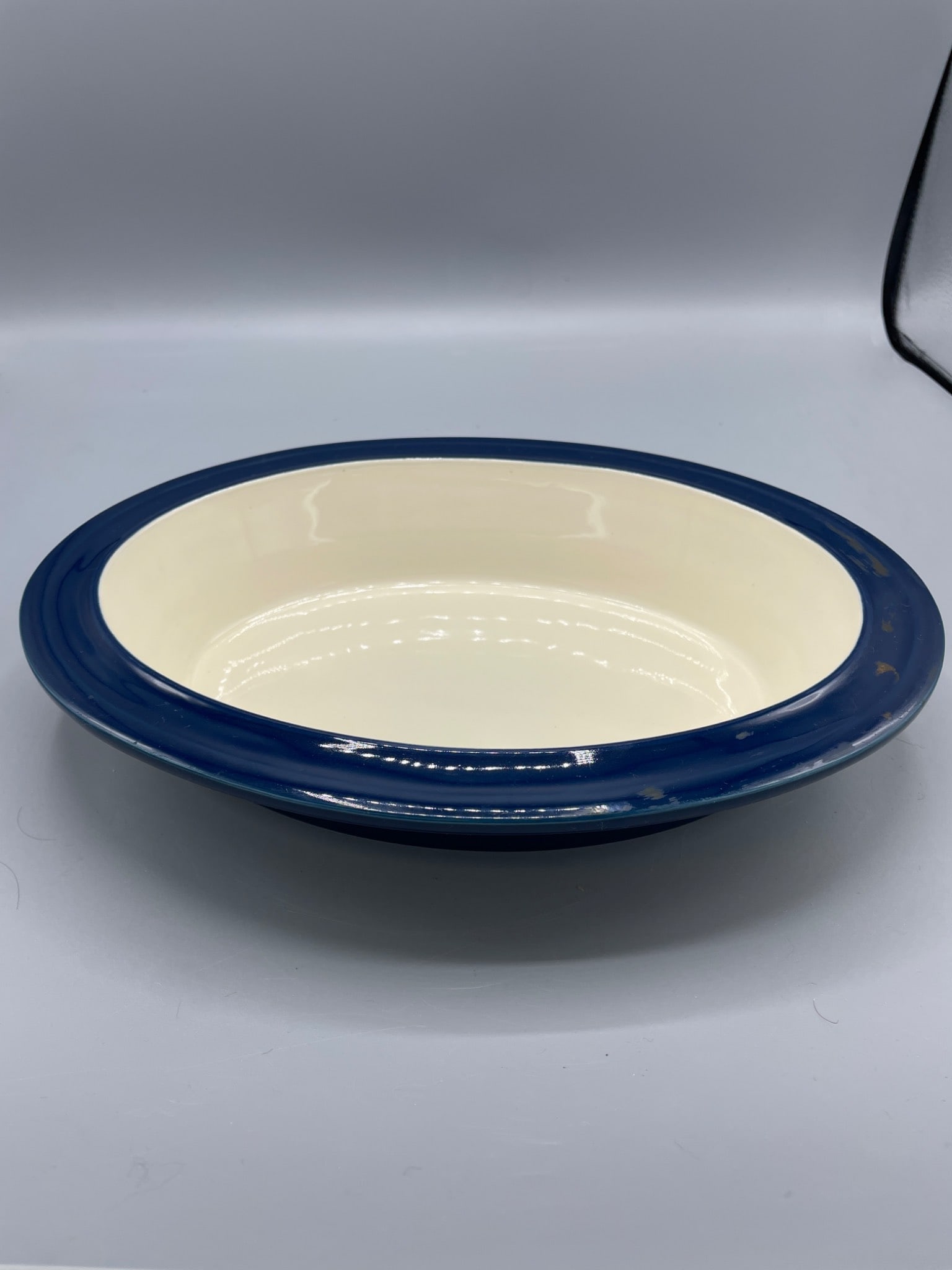 Le Creuset 10 Inch Oval Stoneware Dish in Blue: Le Creuset oval stoneware dish measuring 10 inches (25.4 cm) in diameter. Features a blue outer finish and cream interior. Marked on the bottom with 'Le Creuset,' model number '07.02,' and size