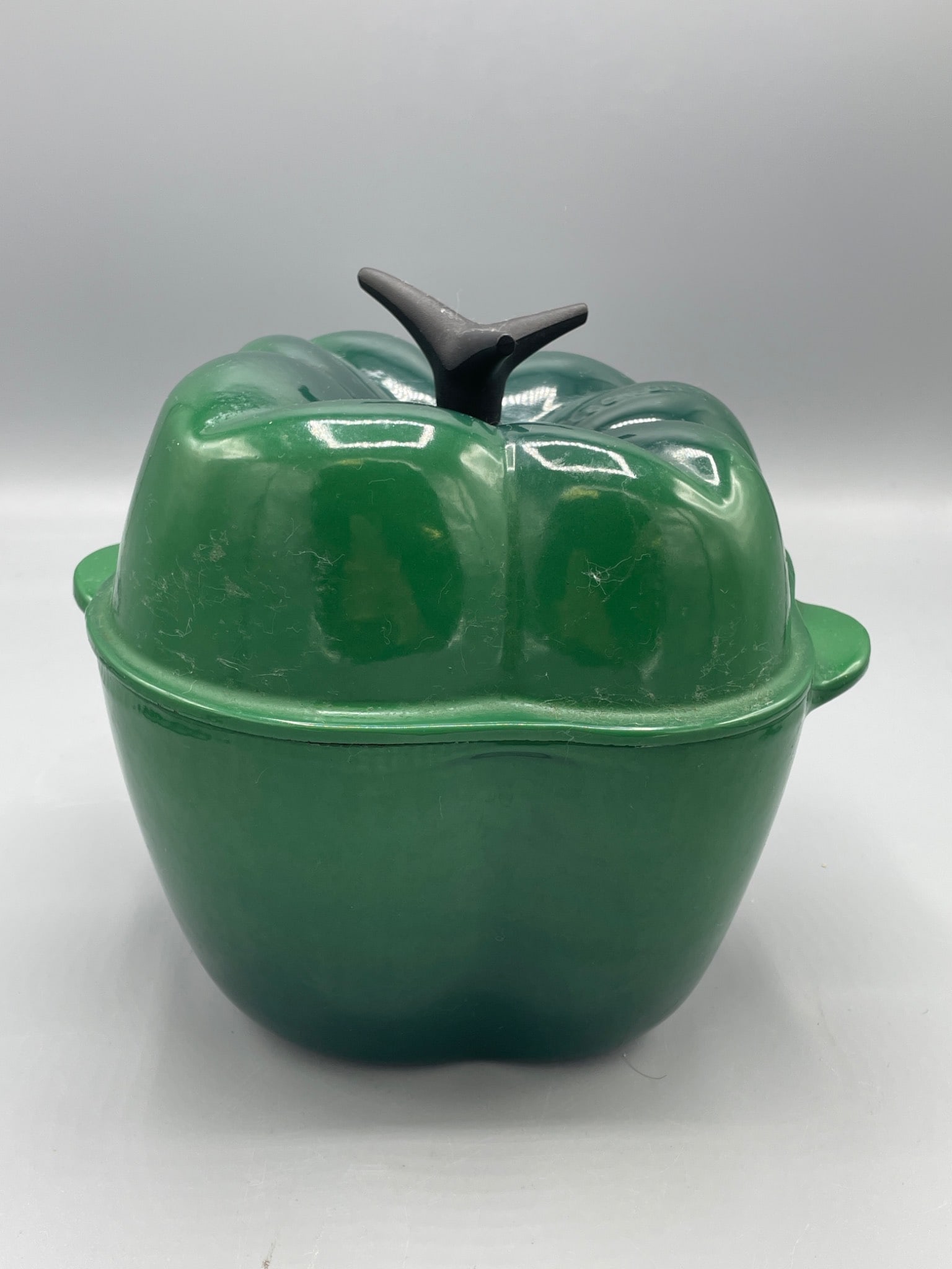 Le Creuset Cast-Iron Green Bell Pepper Dutch Oven, Made in France: This is a cast-iron Dutch oven shaped like a green bell pepper. The item is marked â€˜FRANCE,â€™ indicating its manufacture location. The interior is enamel-coated,