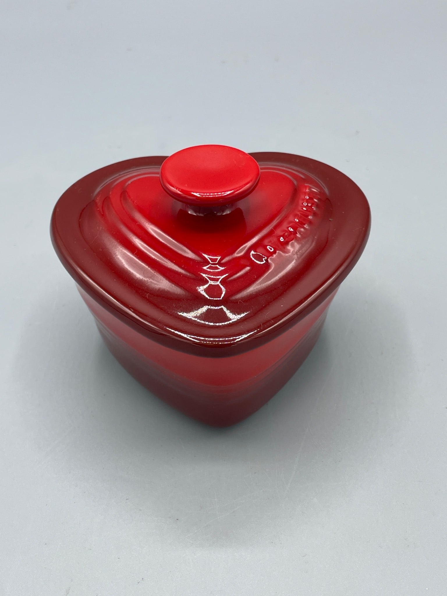 Le Creuset Heart-Shaped Stoneware Covered Dish, Red: Le Creuset heart-shaped stoneware dish with lid in red. Features an interior white enamel finish and exterior glossy red enamel coating. Approximate dimensions: 3 inches tall with lid, 4 inches wide.