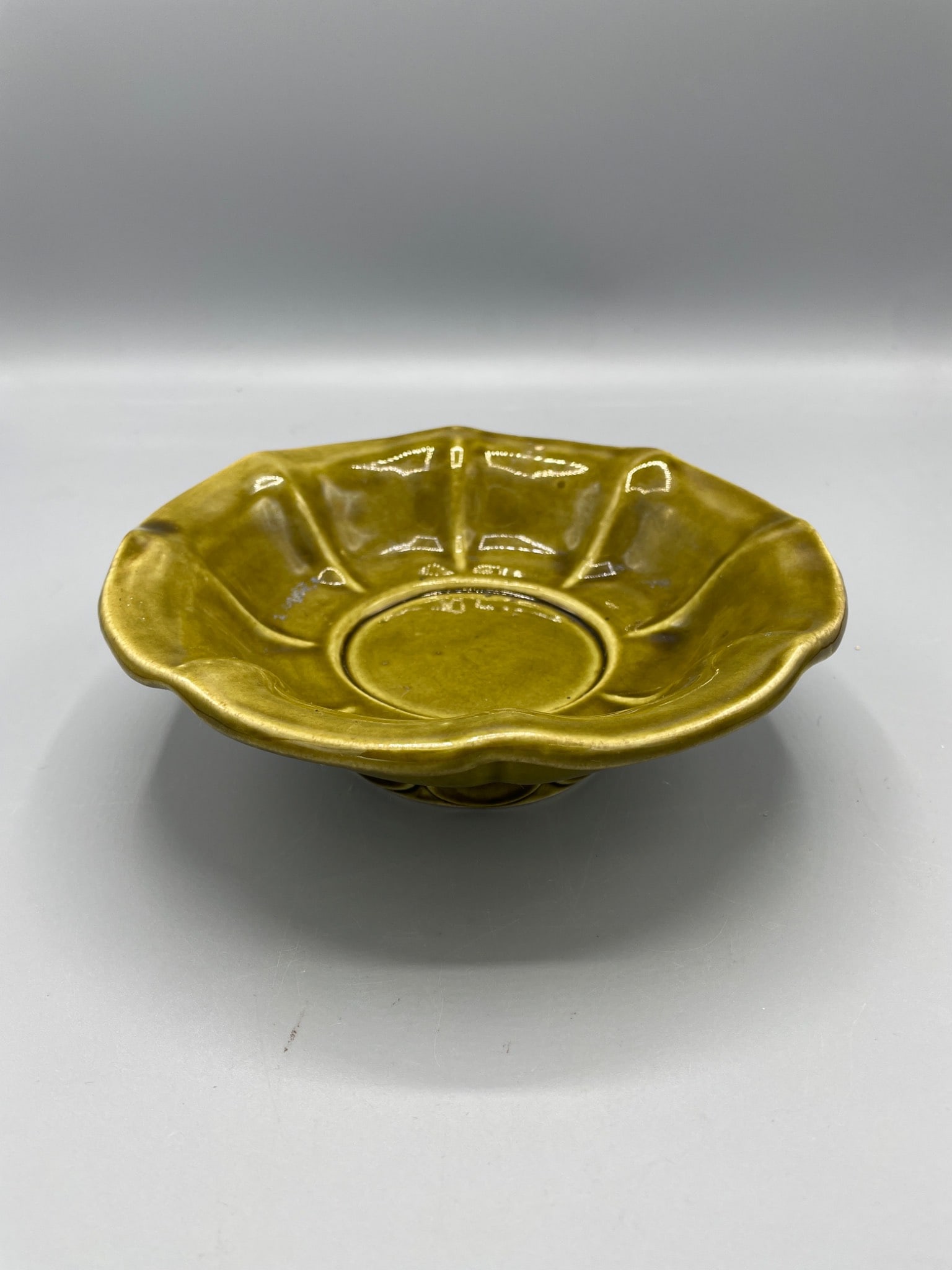 McCoy USA Pottery Yellow Dish with Embossed Details: This item is a McCoy USA pottery dish in yellow glaze. It features embossed details and stands approximately 2 inches in height with a diameter of approximately 8 inches. The dish is stamped on the bo