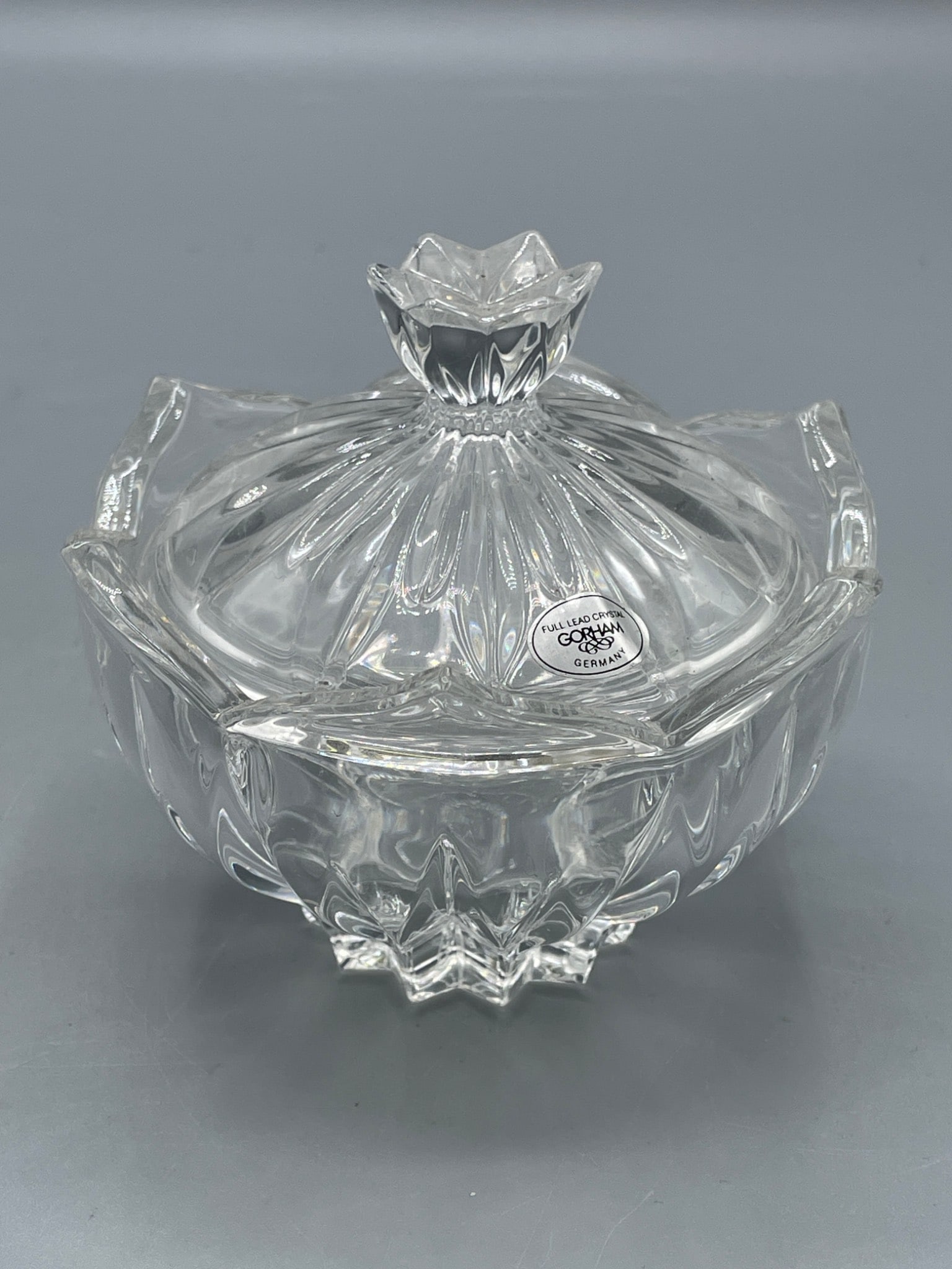 Gorham Full Lead Crystal Lidded Bowl - Germany: This item is a lidded bowl made of full lead crystal, produced by Gorham in Germany. It features a decorative starburst design. The approximate height, including the lid, is 5 inches. The item