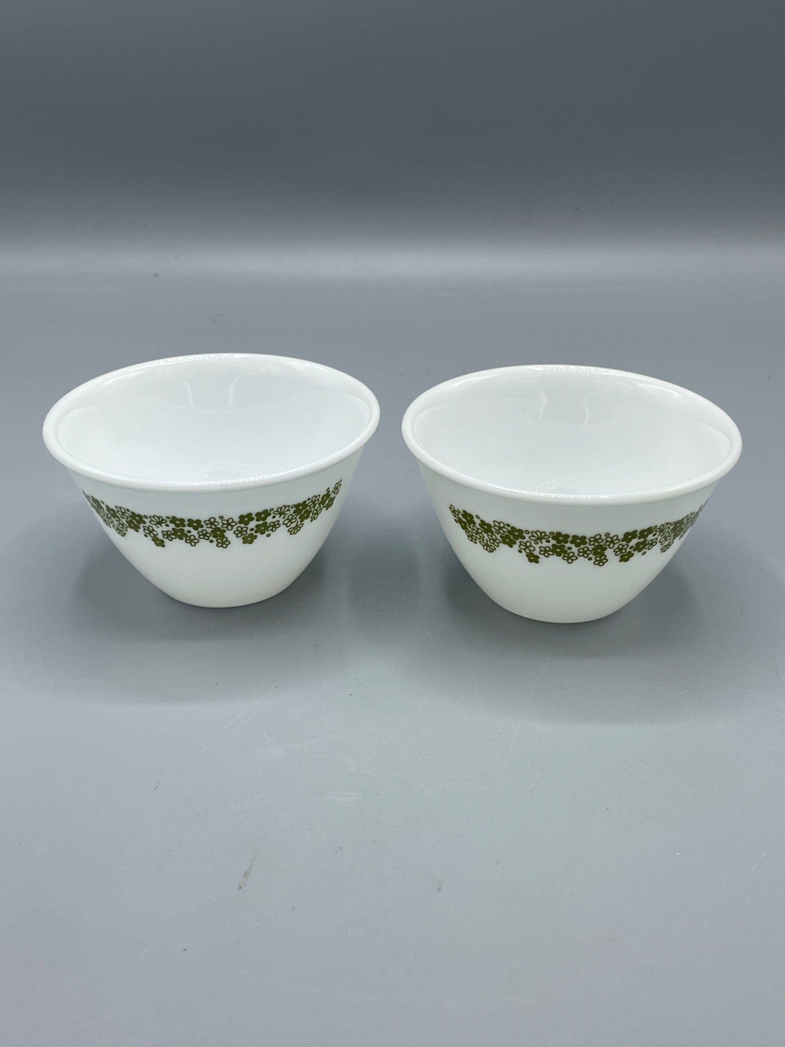 2 Corelle by Corning White Bowls with Green Floral Pattern: 2 white bowls by Corelle, manufactured by Corning (USA). The bowls display a green floral pattern near the rim. Markings on the bottom indicate 'Not for Broiler or Stovetop Use'. Each bowl measures
