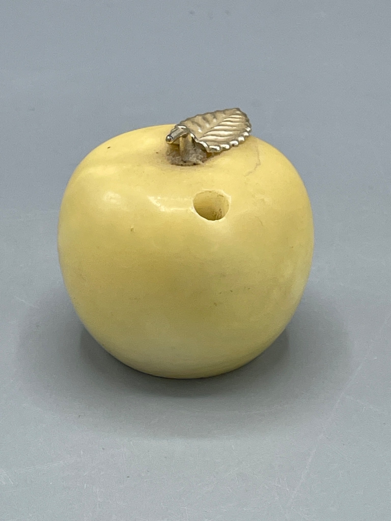 Heavy Apple-Shaped pen holder paper weight With Silver Leaf Detail: A small apple-shaped pen holder, paper weight. Features a silver-tone leaf detail attached to the top. Includes a single hole and a polished base. Approximate dimensions: 2 inches in diameter as
