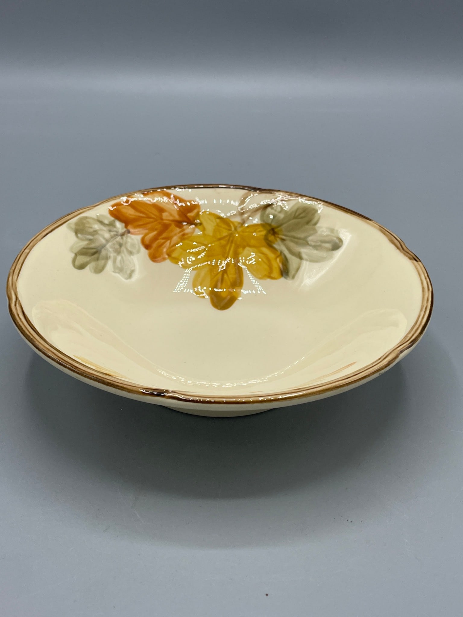 Floral-Design Ceramic Bowl with Gold Trim: This ceramic bowl features a floral design in orange, yellow, and green hues, accented by gold trim along the edge. Measuring approximately 7.5 inches in diameter and 2 inches in height, it is marked 