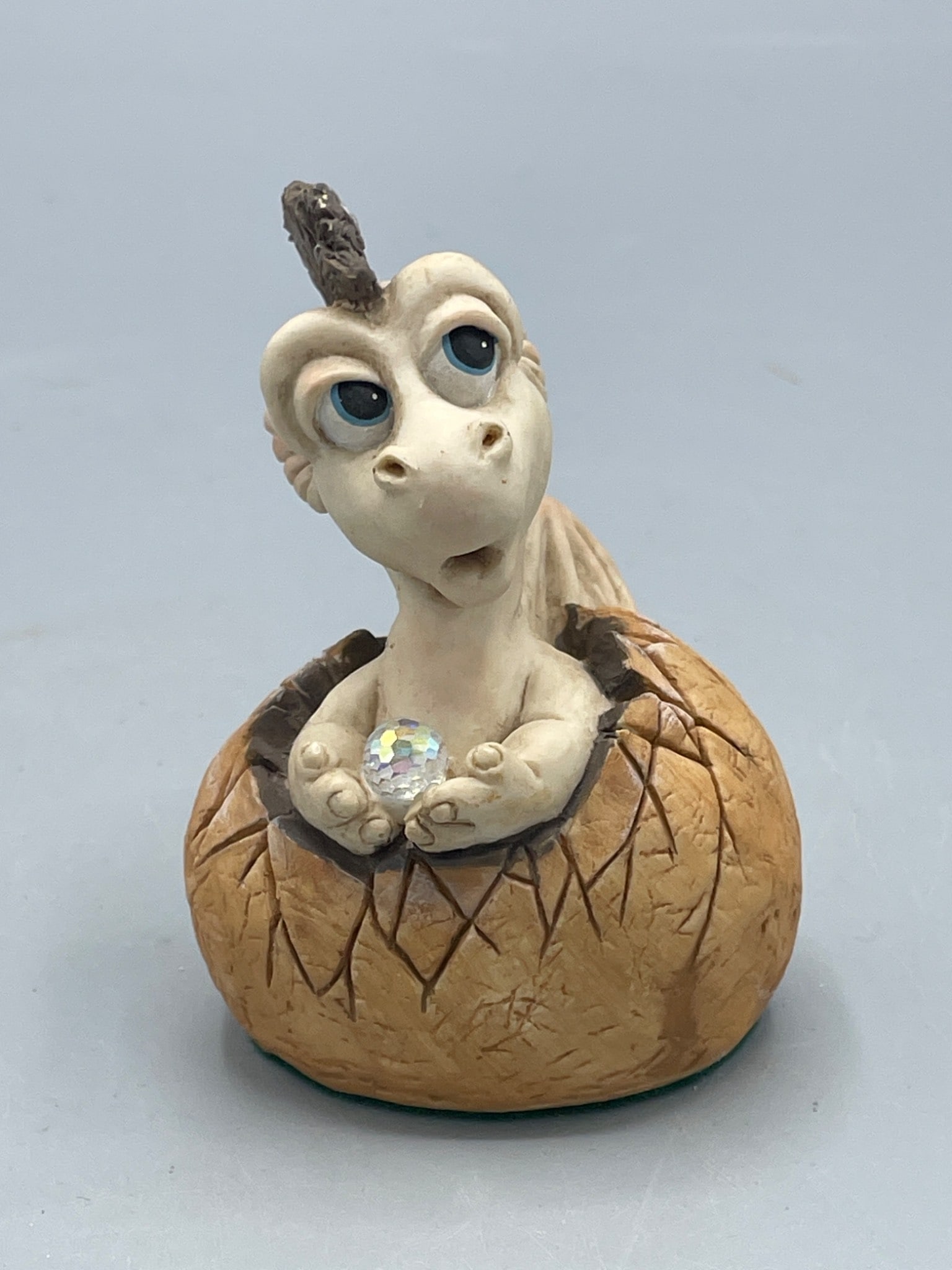 Panton 1988 Tokkel Figurine - Made in England: This is a collectible figurine titled 'Tokkel' created by Panton in 1988. Made in England, it features a dragon-like creature emerging from a cracked shell while holding a small crystal sphere. The