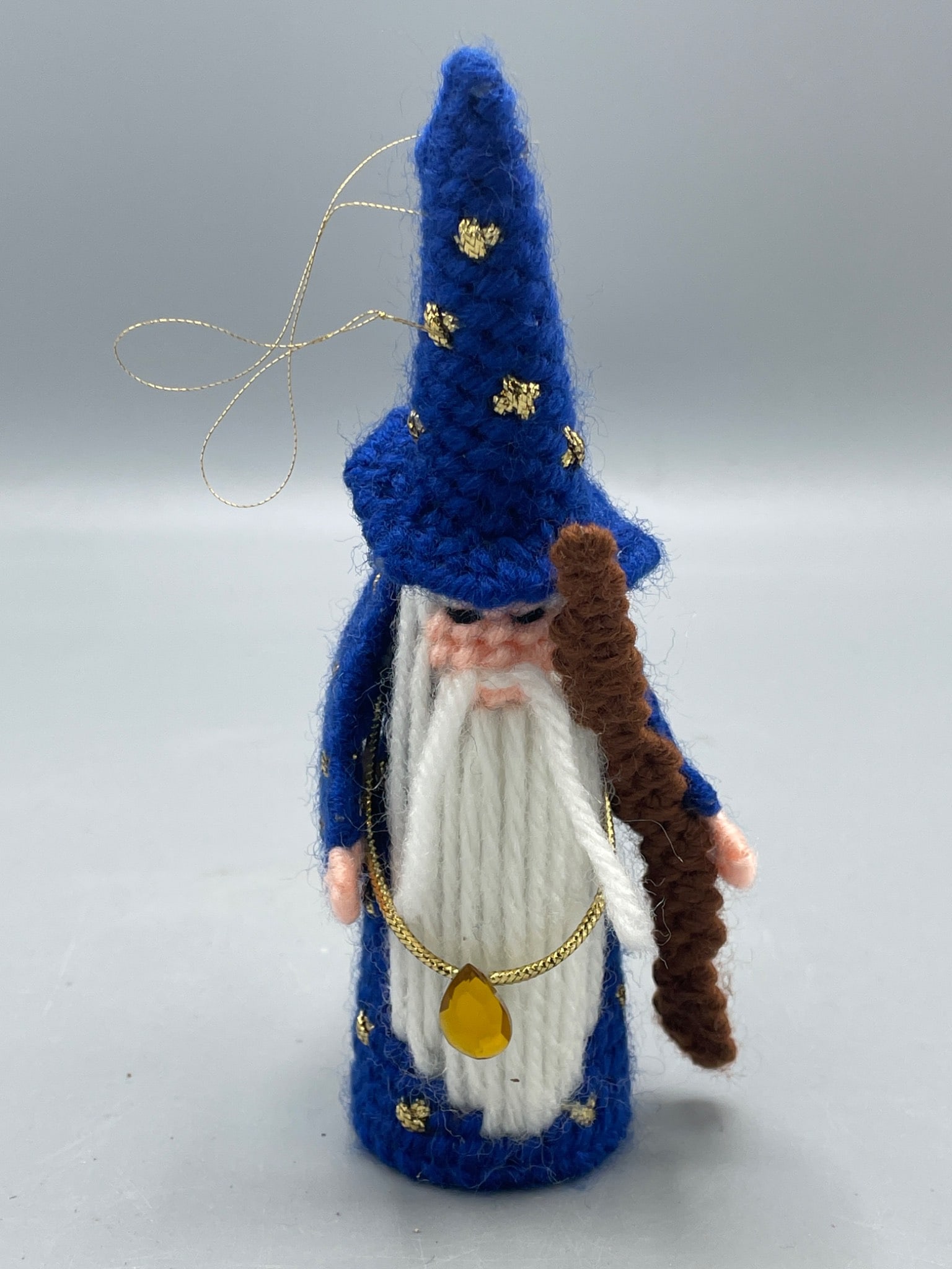 Handmade Blue Wizard Ornament with Knit Detailing: A handmade ornament designed as a wizard figure, featuring a blue knit robe, conical hat with gold accents, and a staff held in hand. Includes a hanging string for display. Approximately 6 inches
