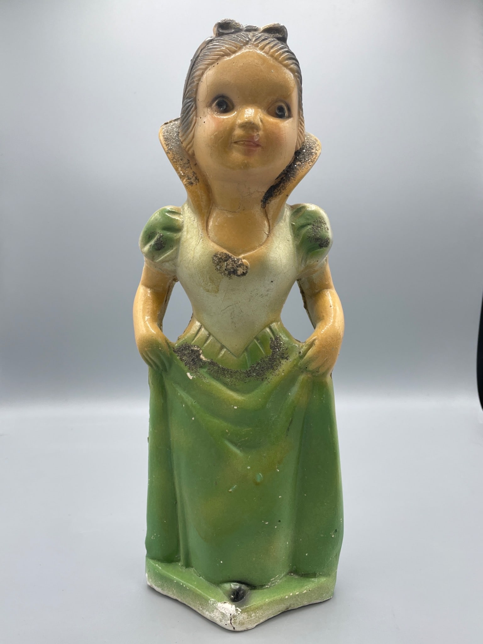 antique Chalkware Figurine Of Snow White In Green Dress, 13 Inches: This is a painted cast iron figurine of a Snow White in a green dress, standing approximately 13 inches tall. The figurine shows signs of wear with visible paint loss and small areas of surface rust. 