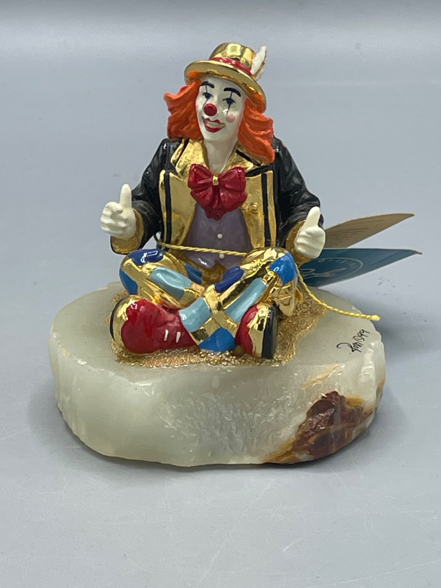 Ron Lee Royal Crest Handcrafted Clown Figurine on Stone Base, Signed Ron â€˜99: This is a handcrafted clown figurine made by Ron Lee. The figurine features bright colors with golden accents and is set on a polished stone base. It is signed by the artist, Ron Lee, and dated