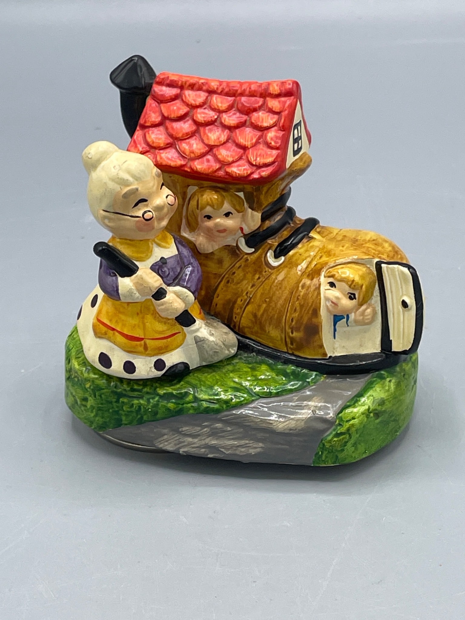 Ceramic Musical Figurine, Old Woman in a Shoe, Made for Spencer, Japan: This ceramic musical figurine features the Old Woman in a Shoe design and is marked 'Made exclusively for Spencer in Japan.' The wind-up mechanism on the bottom plays music and has been tested to be