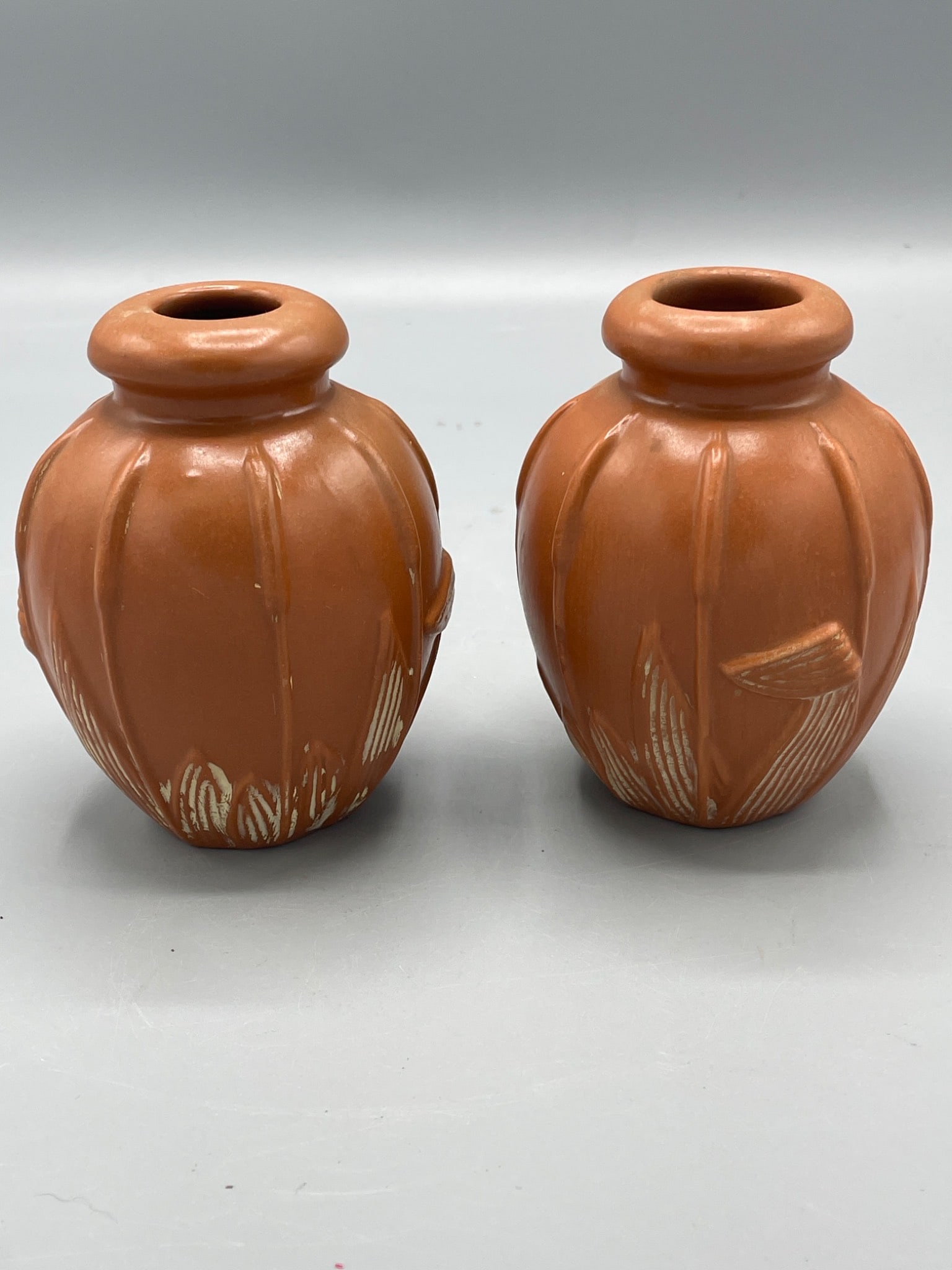1985 Teleflora Gift Vases Made in Brazil: This lot includes a pair of orange ceramic vases, manufactured by Teleflora Inc. in 1985. The vases have a ribbed design with white accent detailing and measure approximately 5 inches in height. Both 