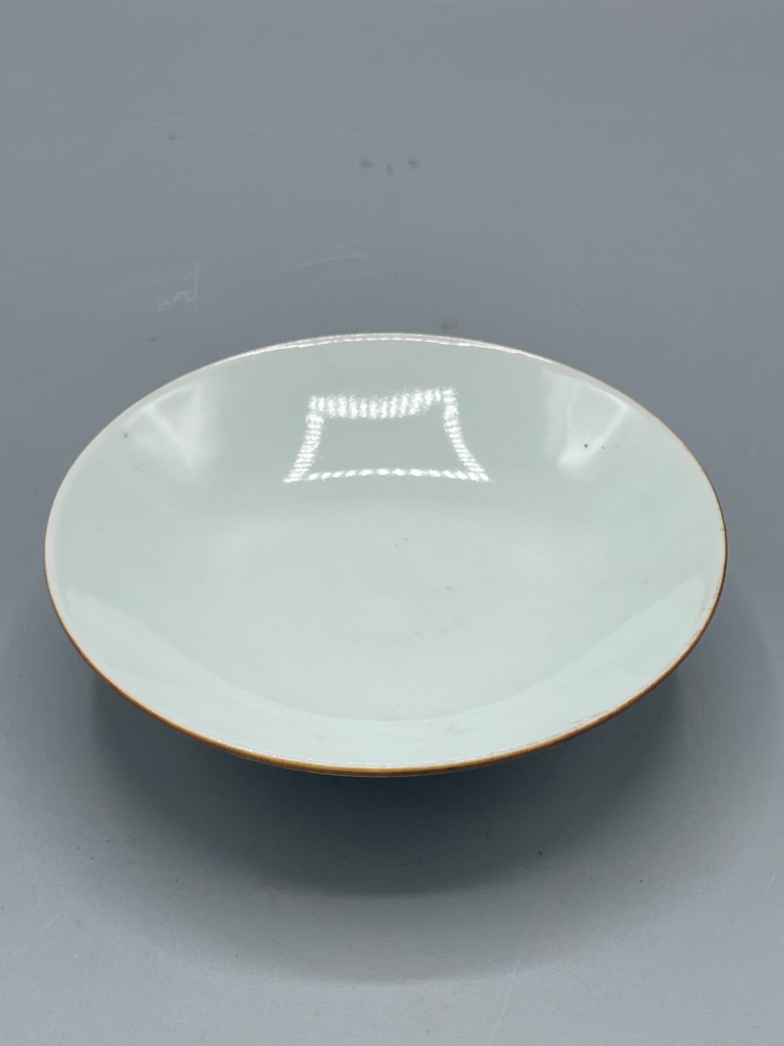 Porcelain Bowl with Blue and White Underglaze Designs: A porcelain bowl with a plain off-white interior and an exterior featuring blue and white underglaze painted designs. The base includes circular patterns framing individual motifs. The bowl has a