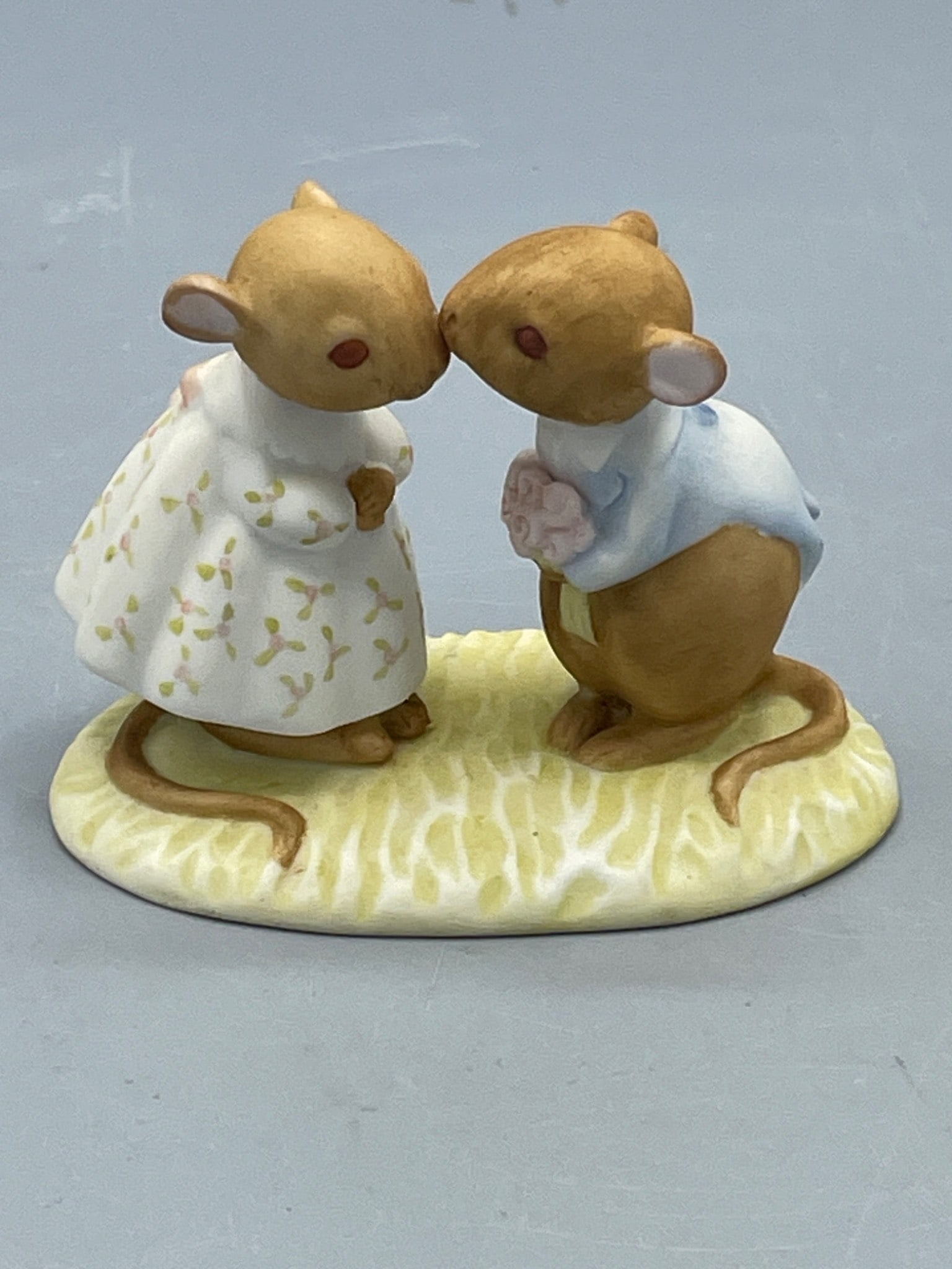 Tiny Talk Genuine Porcelain Figurine by WWA Inc, 1985: This is a Tiny Talk porcelain figurine produced by WWA Inc in 1985. The piece features two mice, one wearing a white dress with floral patterns and the other dressed in a blue shirt, standing on an ov