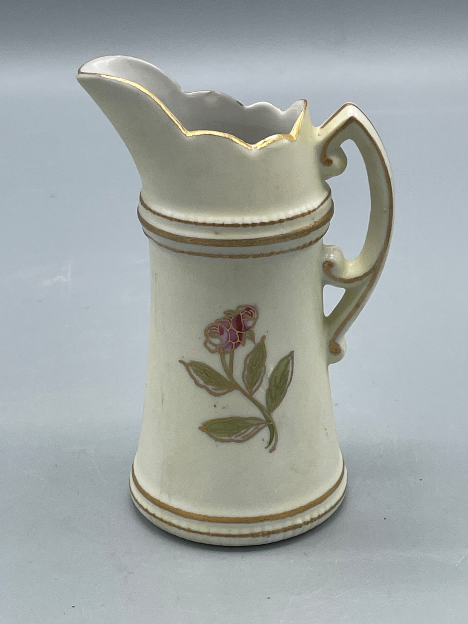 Meissen Porcelain Creamer/Pitcher, Model 6871 R, Scalloped Edge, Floral Design: A Meissen porcelain creamer/pitcher with a scalloped rim, hand-painted flower motif, and gold accenting. Marked on the base with the traditional crossed swords, a red line, model number '6871 R', and 