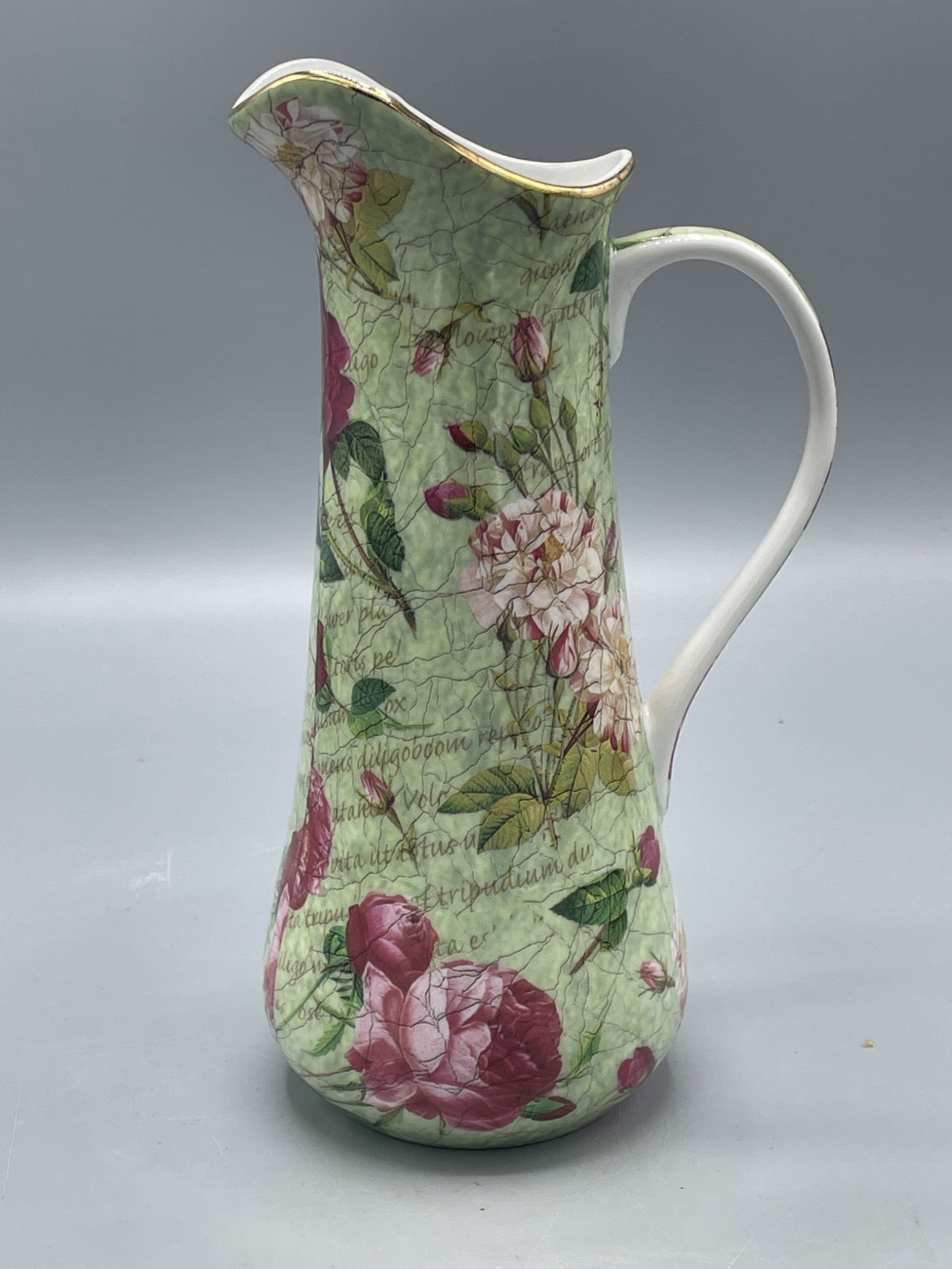 Floral Porcelain Pitcher by J. Godinger & Co., 10-inch Height: This is a porcelain pitcher from the 'Antique Reflections' collection by J. Godinger & Co. It features a floral design with pink roses on a green background and a gold-accented rim. The pitcher