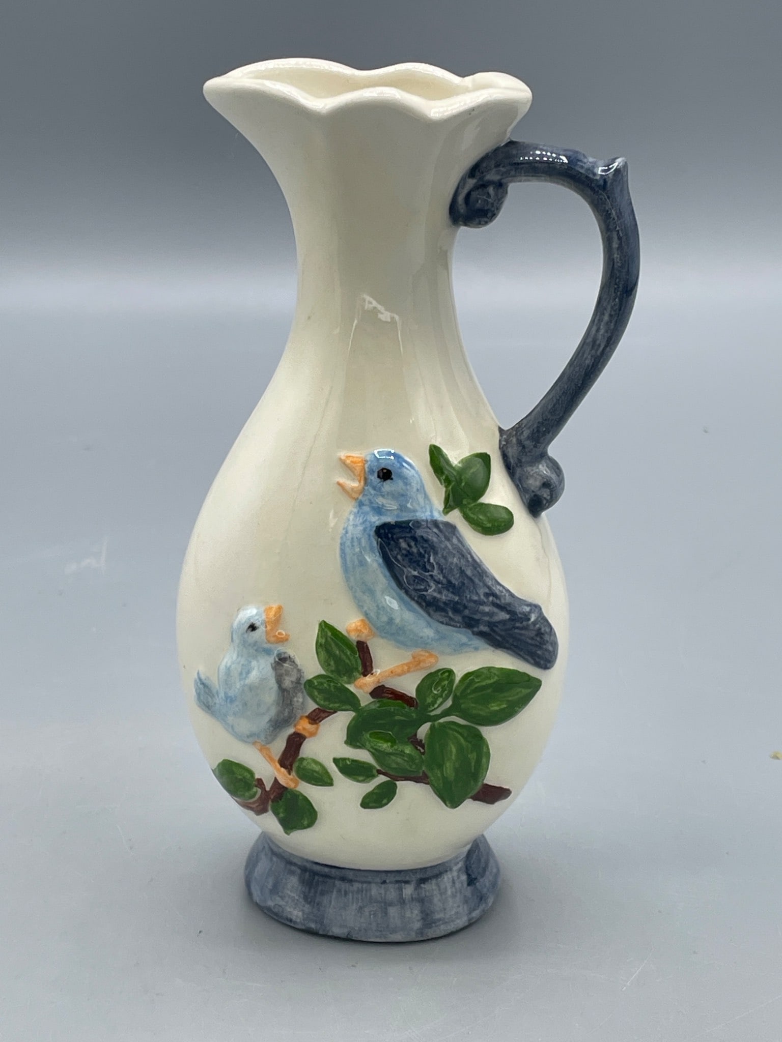 Ceramic Pitcher with Bird Motif, Marked M003: A small ceramic pitcher featuring a sculpted bird motif on its surface, with measurements indicating a height of approximately 7 inches. The item is marked 'M003' on the base, although the