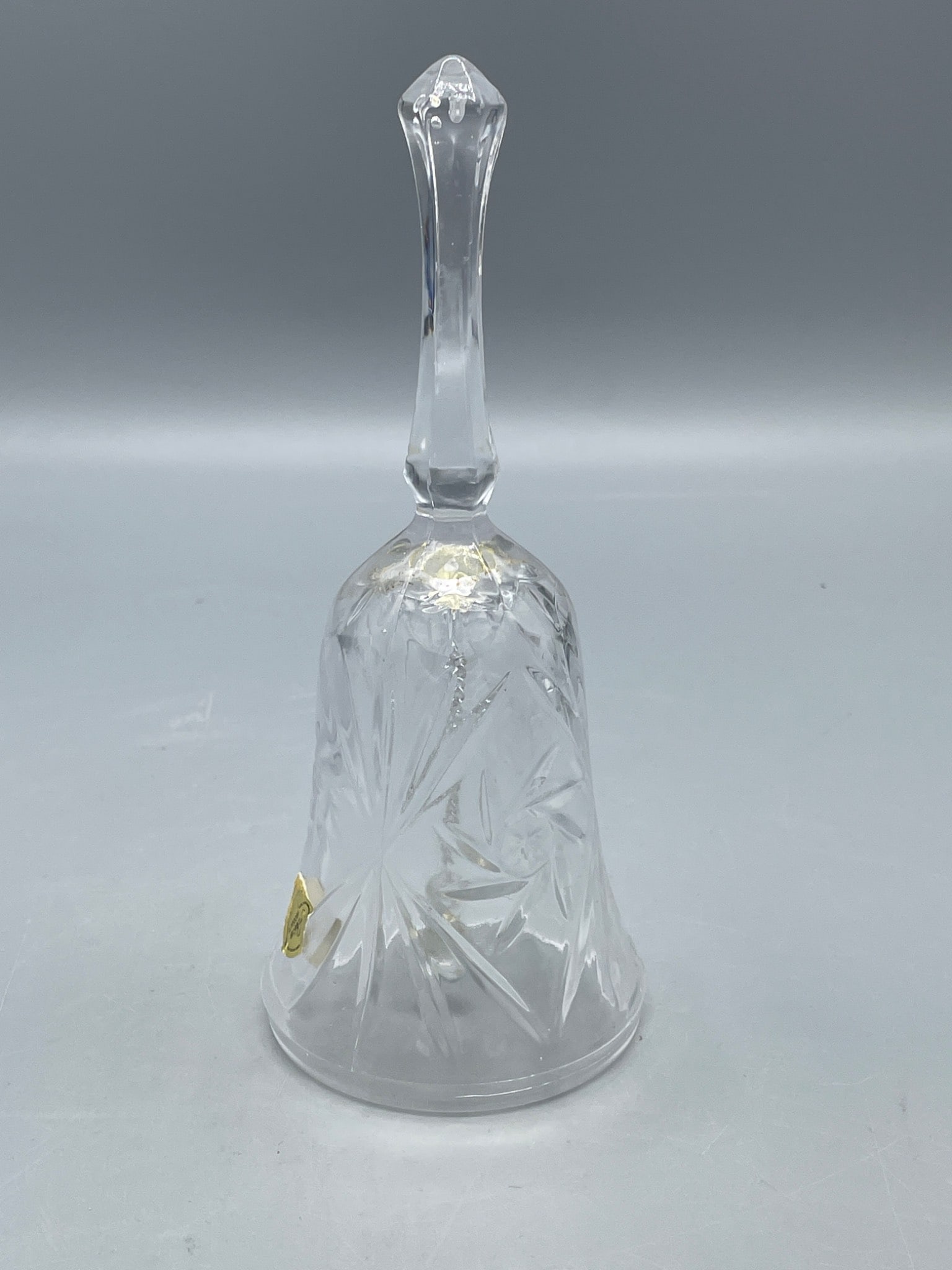 Crystal Bell with Starburst Pattern and Gold Label Mark: This crystal bell features a decorative starburst pattern on its surface and is marked with a gold label reading 'Taiwan' and 'Z Products'. The bell includes a smooth handle and an attached glass