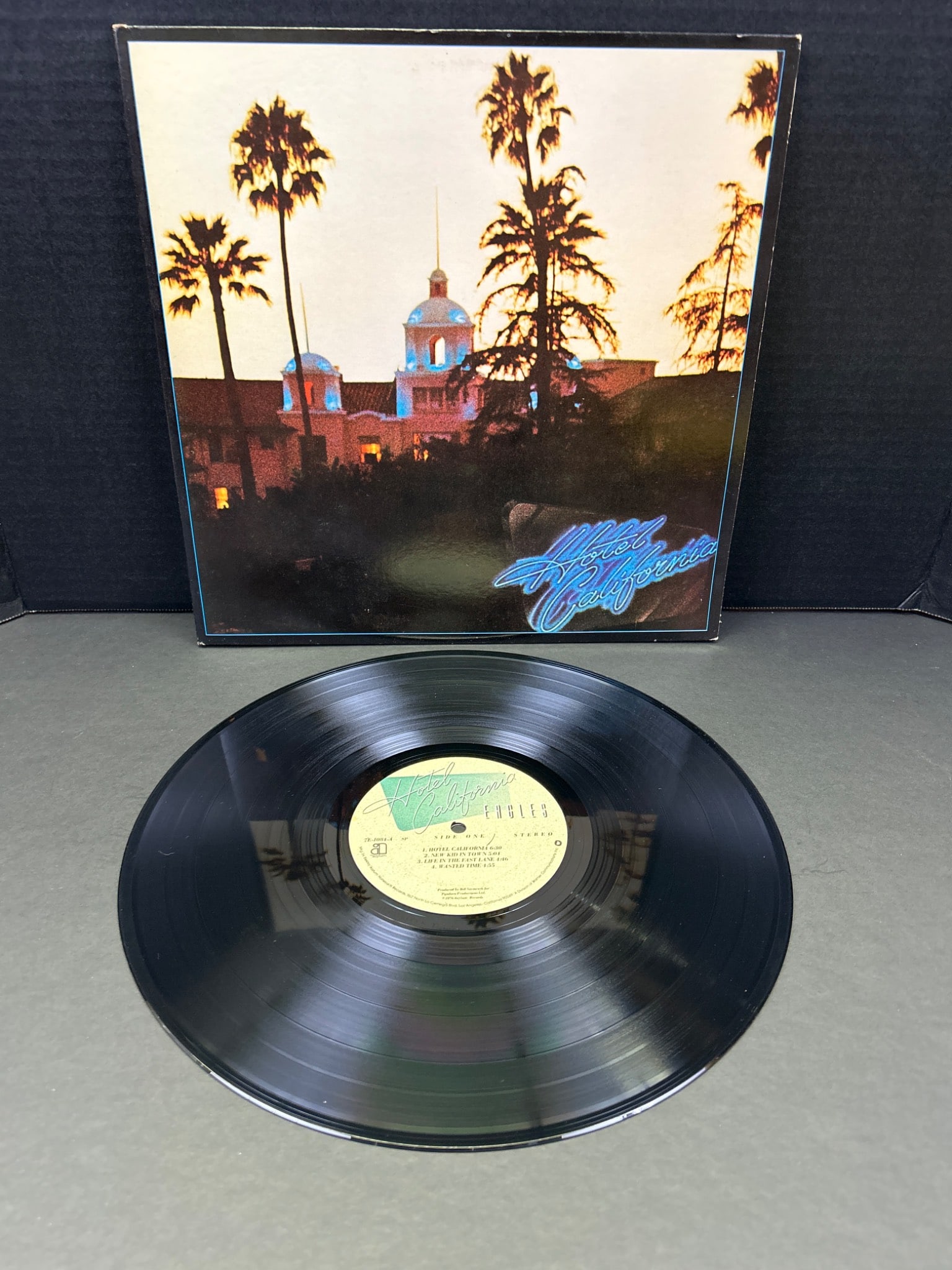 Eagles - Hotel California Vinyl Record, Original Pressing: This listing features the Eagles' "Hotel California" vinyl record. The album is an original pressing and includes the iconic gatefold cover with lyrics and artwork. The vinyl appears to be in