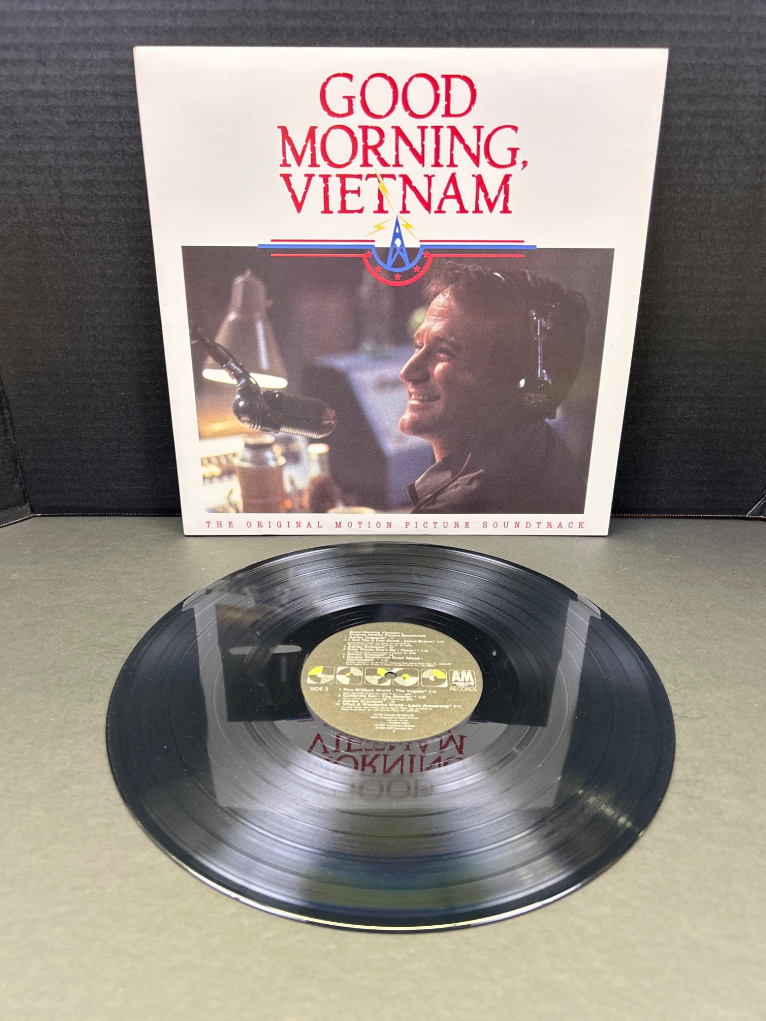 Good Morning, Vietnam Official Motion Picture Soundtrack Vinyl Record: This is the official soundtrack vinyl record for the movie 'Good Morning, Vietnam.' Released by A&M Records in 1987, the LP features various tracks from the film, as well as comedic interludes by