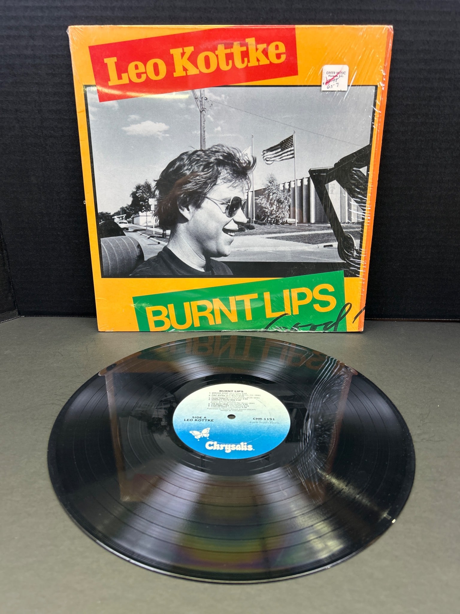Leo Kottke 'Burnt Lips' Vinyl Record Album, Chrysalis CHR 1204: This is a vinyl record of the album 'Burnt Lips' by Leo Kottke, released under Chrysalis Records with catalog number CHR 1204. The album cover and record are shown, indicating the original packaging