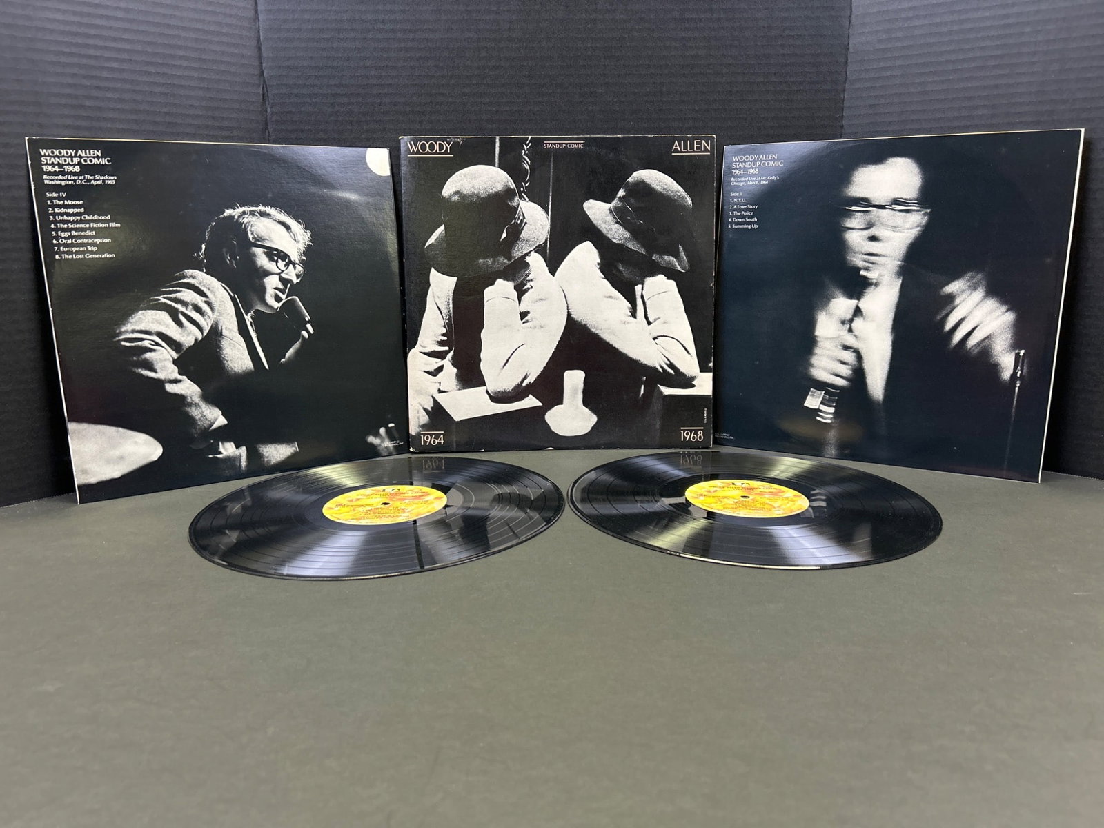 Woody Allenâ€™s Comedy Albums with Gatefold Cover: This lot includes two vinyl records featuring Woody Allenâ€™s comedic performances. The albums appear to feature gatefold covers with reviews and remarks about the artist and the cont