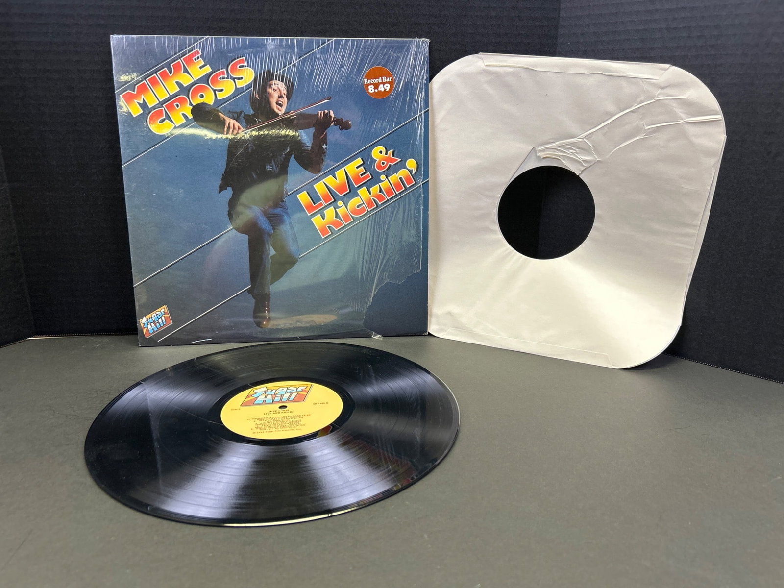 Mike Cross Live & Kickinâ€™ Vinyl Record LP Album with Sleeve: This listing features Mike Crossâ€™s â€˜Live & Kickinâ€ vinyl record album, complete with its original sleeve. The albumâ€™s vinyl ap
