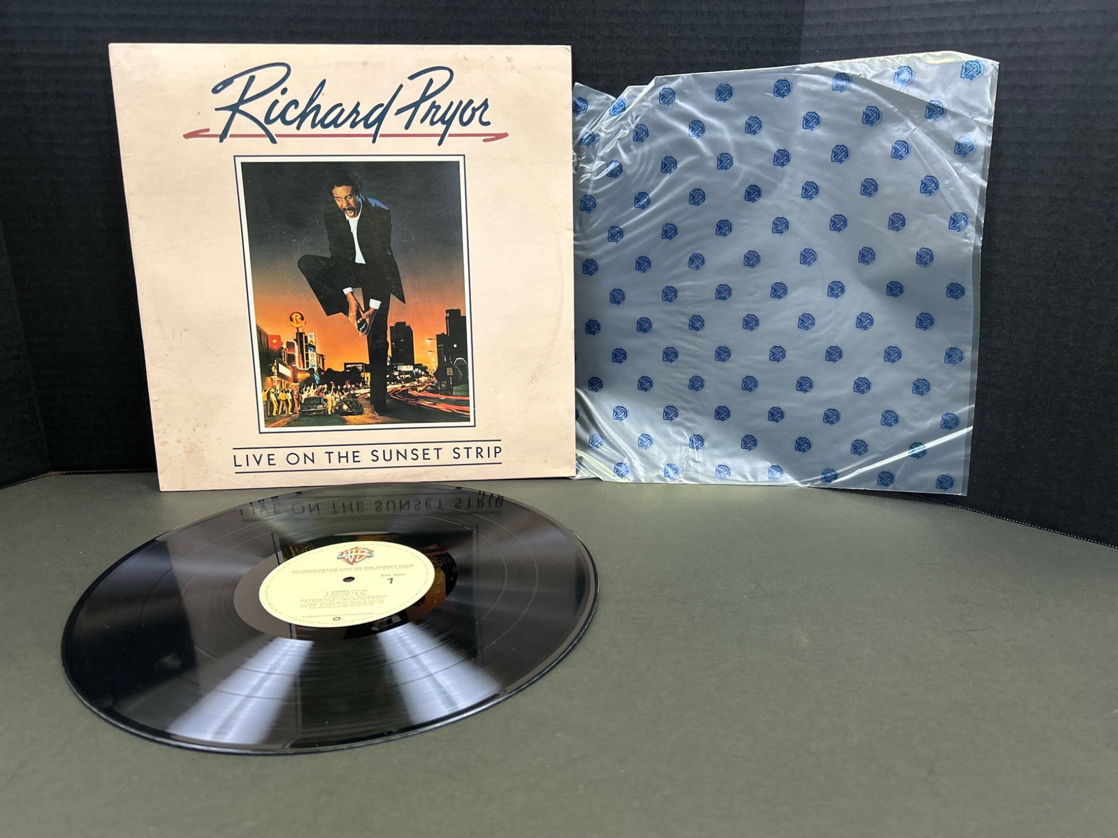 Richard Pryor Live on the Sunset Strip Vinyl Record: Richard Pryor's 'Live on the Sunset Strip' vinyl record, released by Warner Bros. Records in 1982. The LP comes in its original sleeve featuring cover art and includes a protective inner sleeve. Recor