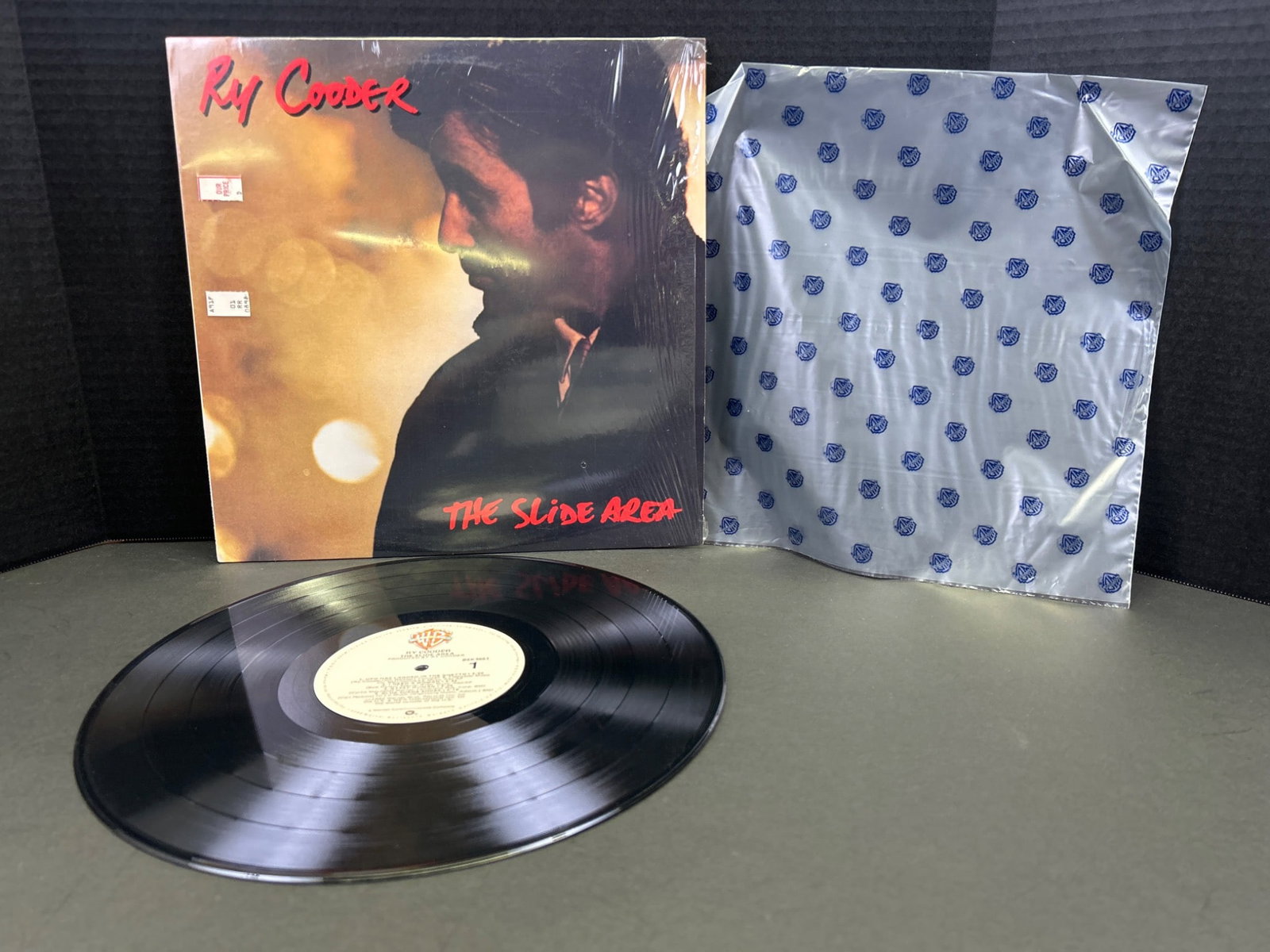 Ry Cooder 'The Slide Area' Vinyl LP Album with Original Sleeve: Ry Cooder's 'The Slide Area' vinyl LP album, released in 1982 by Warner Bros. Records (catalog number: 9 23686-1). Includes the original outer cover and inner sleeve with lyrics. The record condition 