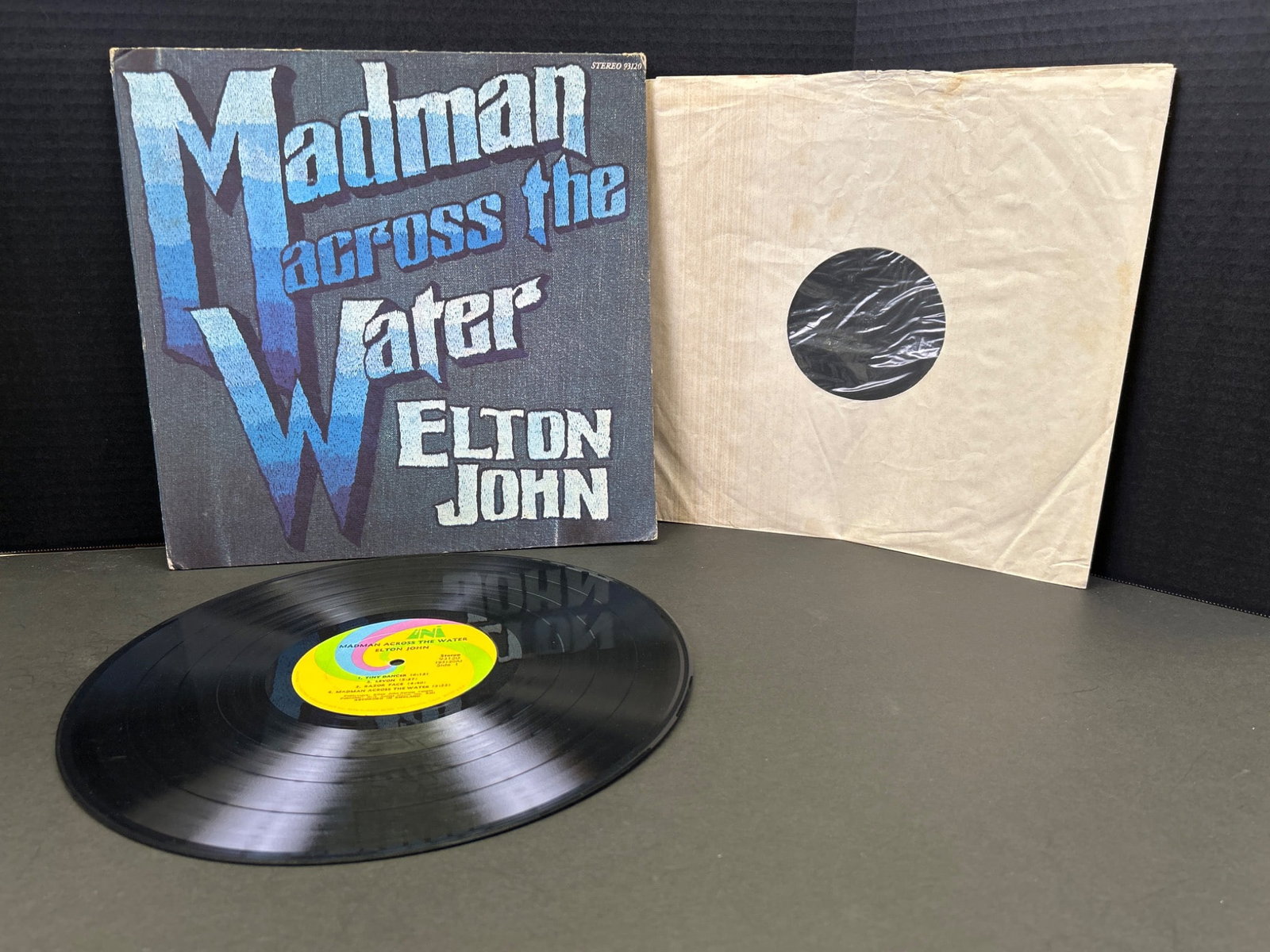 Elton John 'Madman Across the Water' Vinyl LP Album, 1971: Elton John's 'Madman Across the Water' vinyl LP album, released in 1971 under DJM/UNI Records, catalog number DJLPH420. Includes gatefold sleeve with attached booklet. Condition shows some wear to the