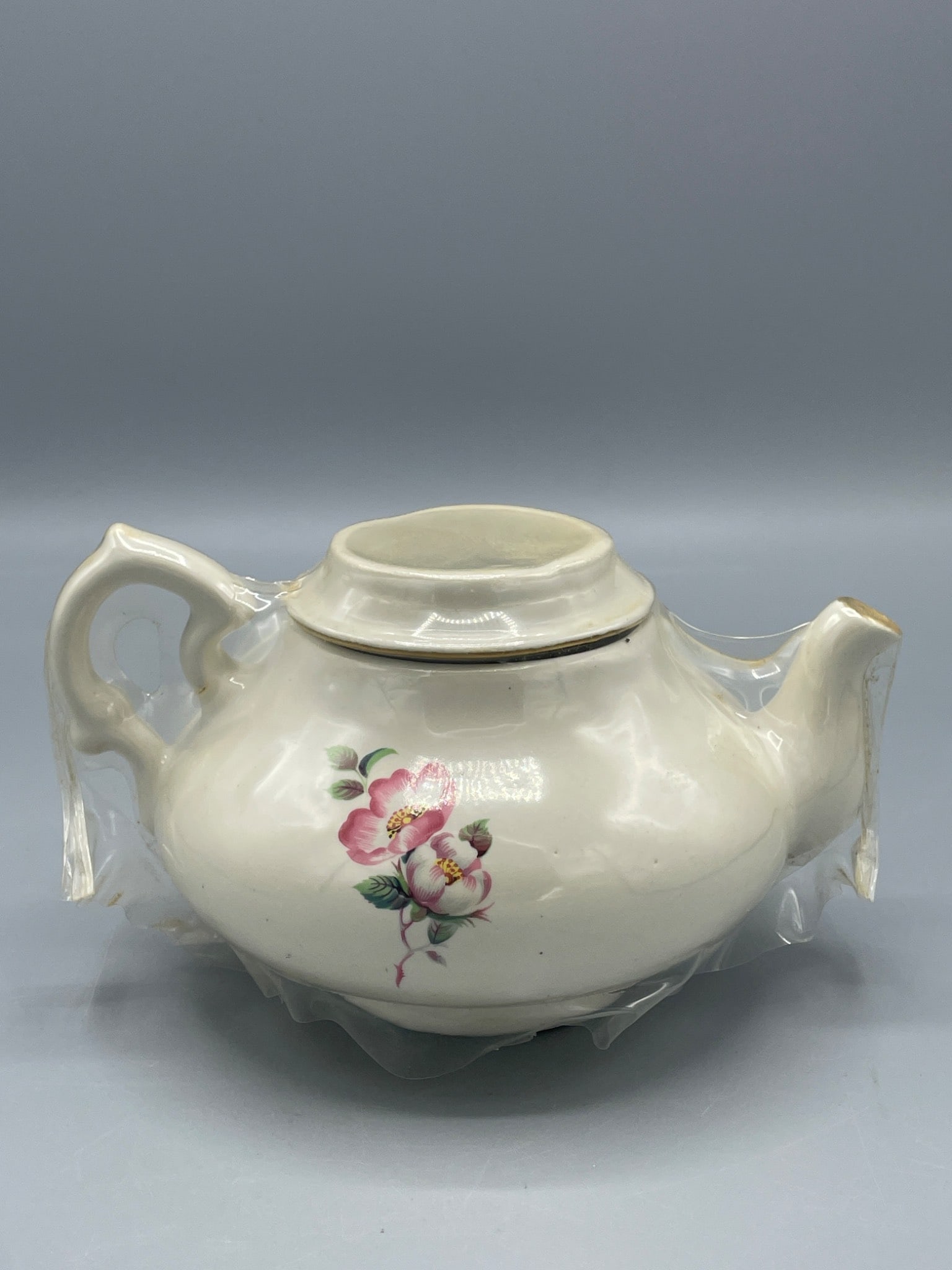 House of Webster Teapot with Pink Floral Design and Gold Rim Accents: Ceramic teapot featuring a pink floral design on both sides and gold rim accents. The makerâ€™s mark on the base.Â Approximate dimensions: 5 inches tall and 8.5 inches
