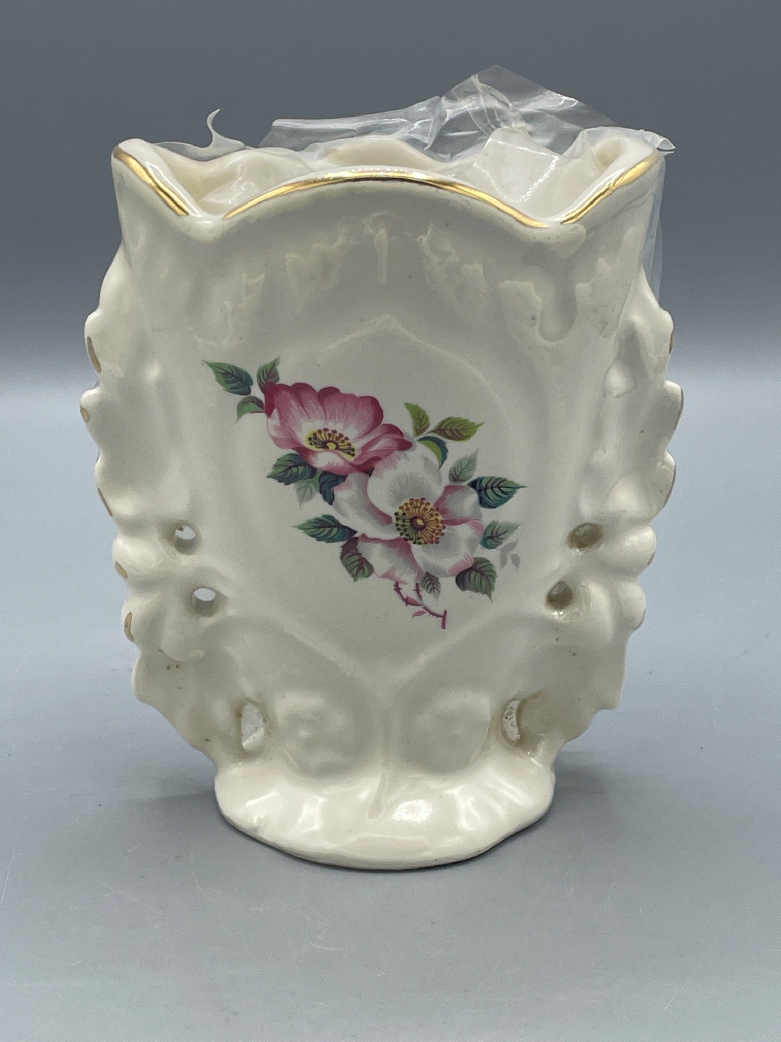House of Webster Ceramic Floral Vase With Gold Trim, Scalloped Edge and Floral Design: A ceramic vase featuring floral designs on both sides, scalloped edges, and pierced detailing along the sides. The vase is finished with gold trim along the rim. Approximate height is 6 inches based o