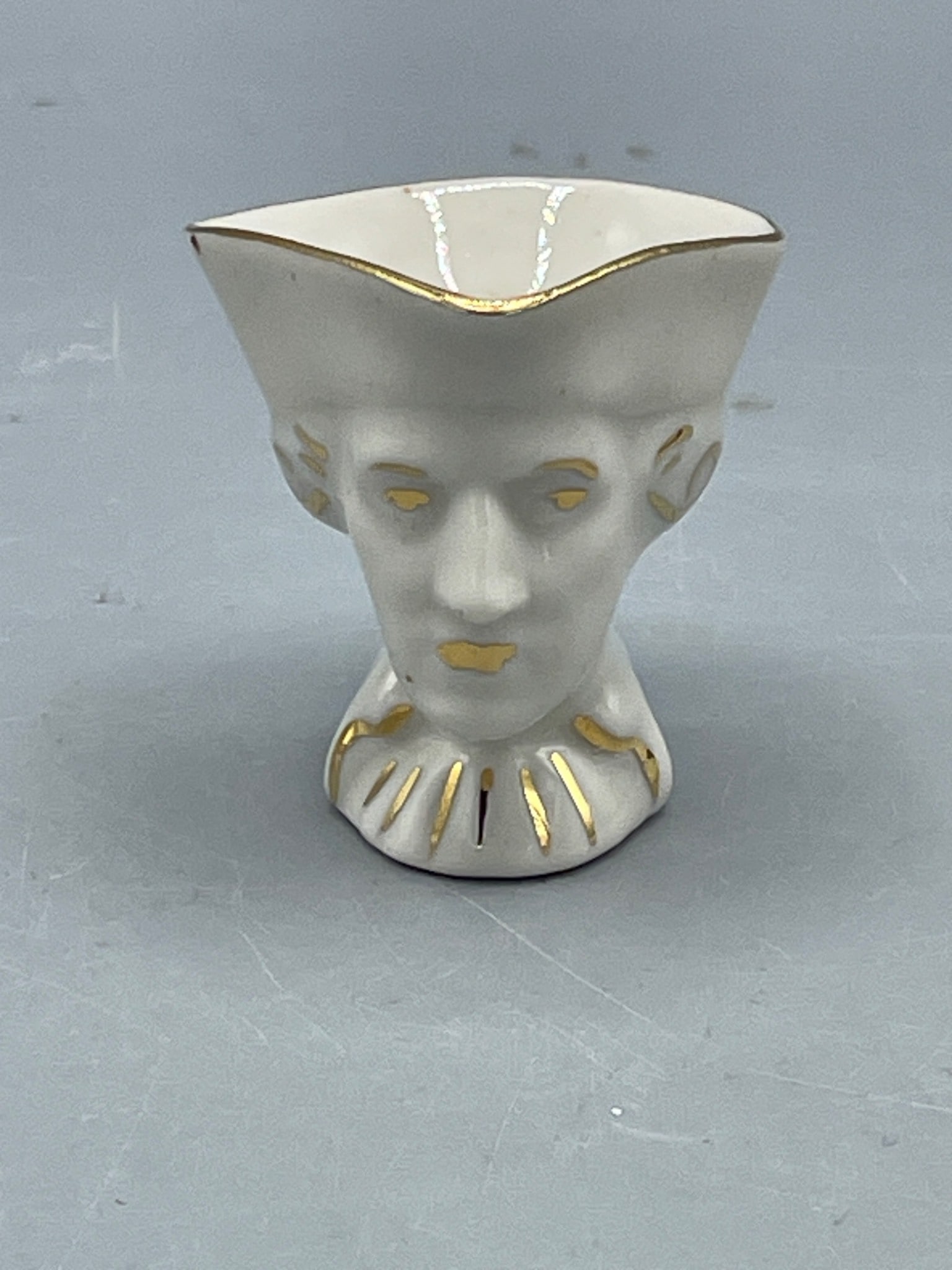 Toby style mug Ceramic Face-Shaped Small Pitcher with Gold Detailing: A small ceramic pitcher designed in the shape of a face, featuring gold-painted accents on the rim, facial details, and collar. The item measures approximately 3 inches in height. The base is