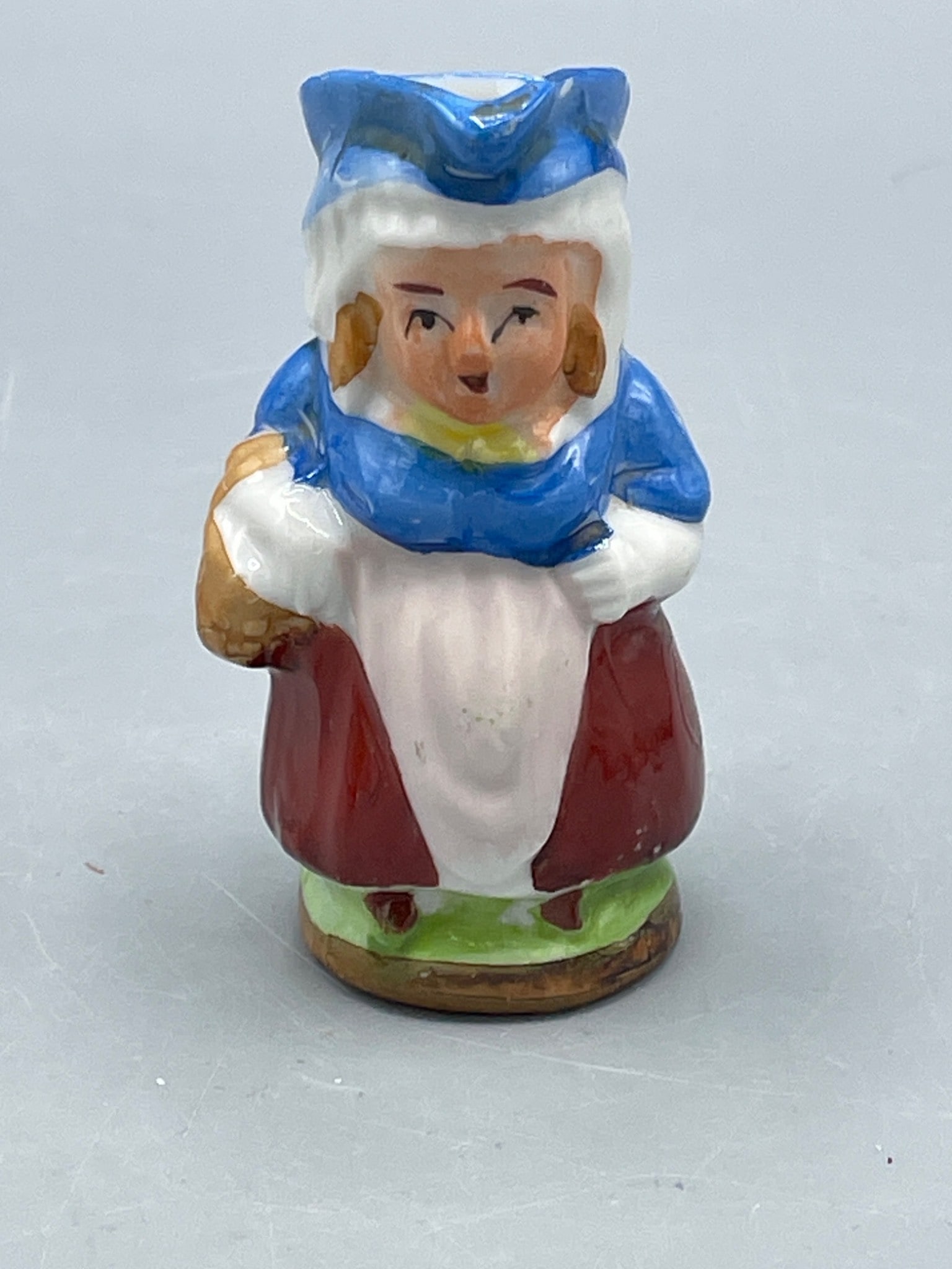 Toby style pitcher: This item is a small ceramic pitcher or figurine featuring a hand-painted design of a female figure in folk costume. It measures approximately 3 inches in height. The bottom is marked