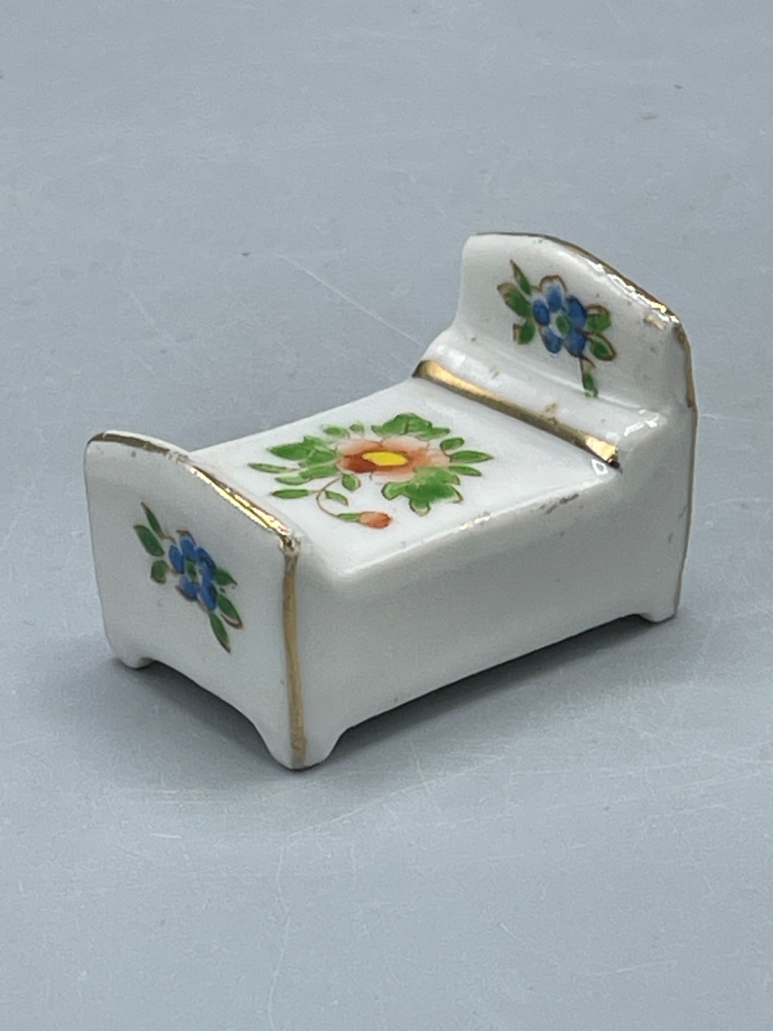 Porcelain Small Bed Figurine with Floral Design, Occupied Japan Mark: This is a porcelain small bed figurine decorated with floral patterns and gold accents. The bottom is marked 'Made in Occupied Japan,' indicating production during the post-WWII era (1945-1952). It